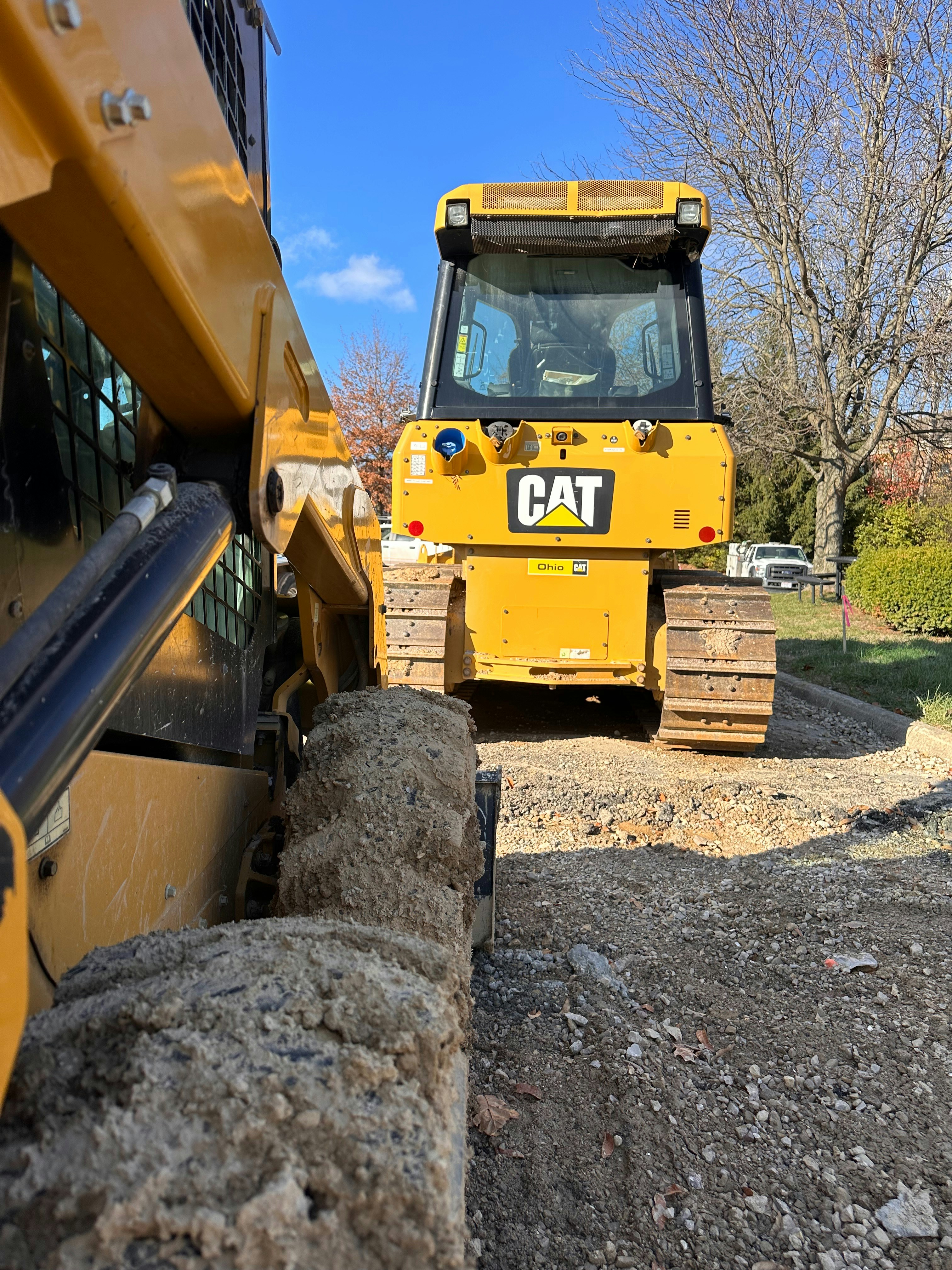 Yellow crawler bulldozer pushing earth at construction site, tracks on rough terrain