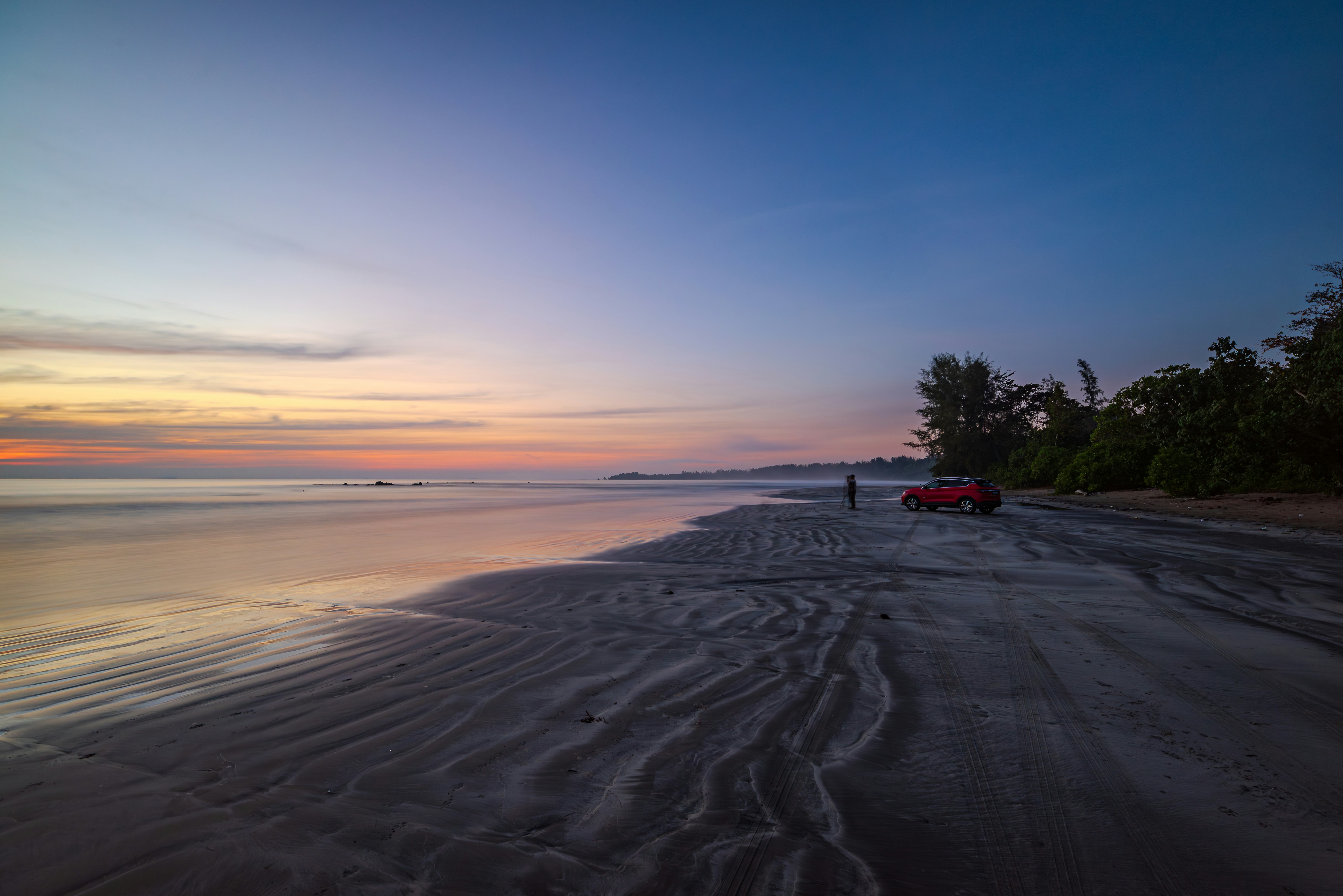 A person walking on a beach at sunset