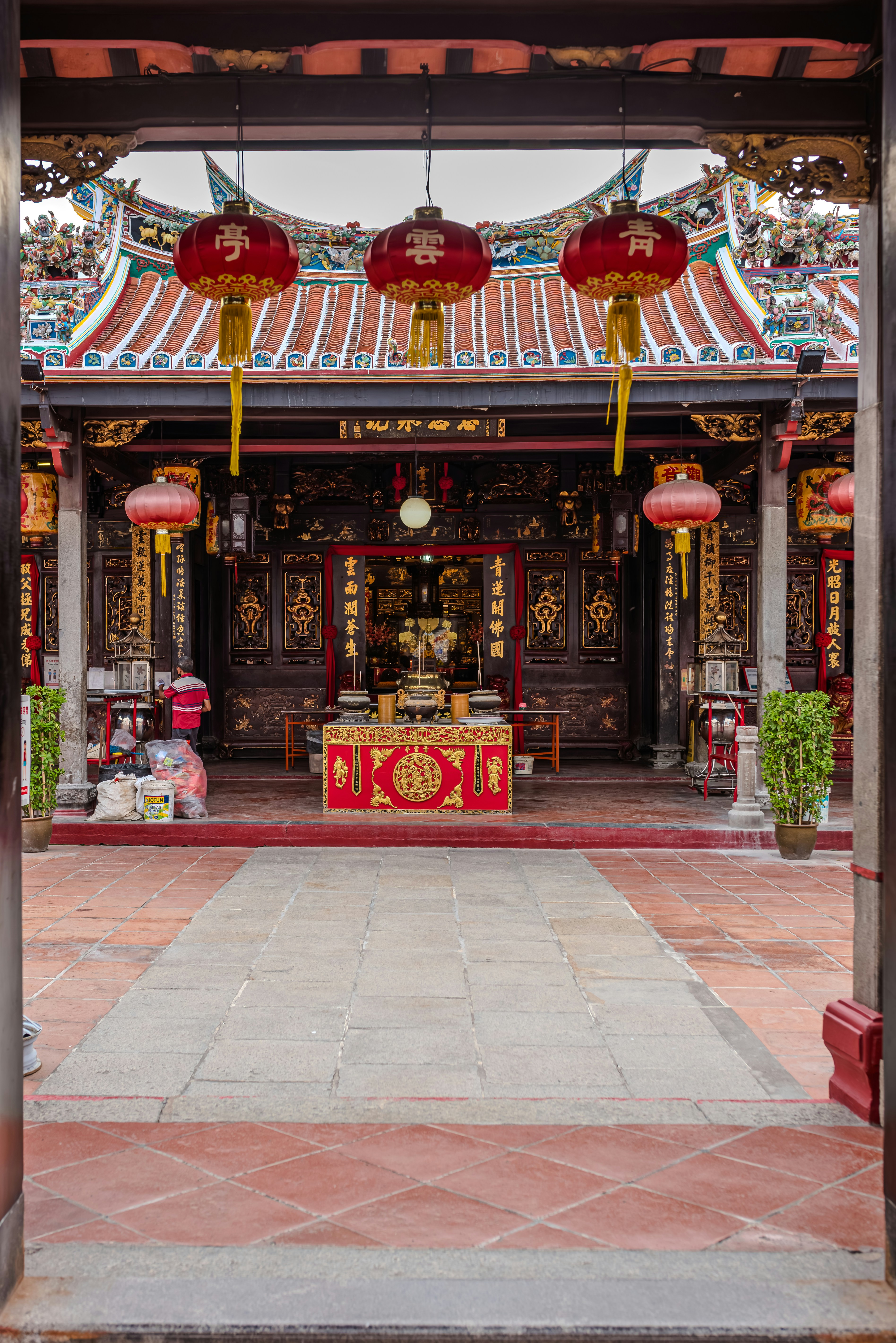 A red and gold building with lanterns hanging from it's roof