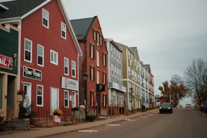 A row of houses on a street with a car parked on the side of the