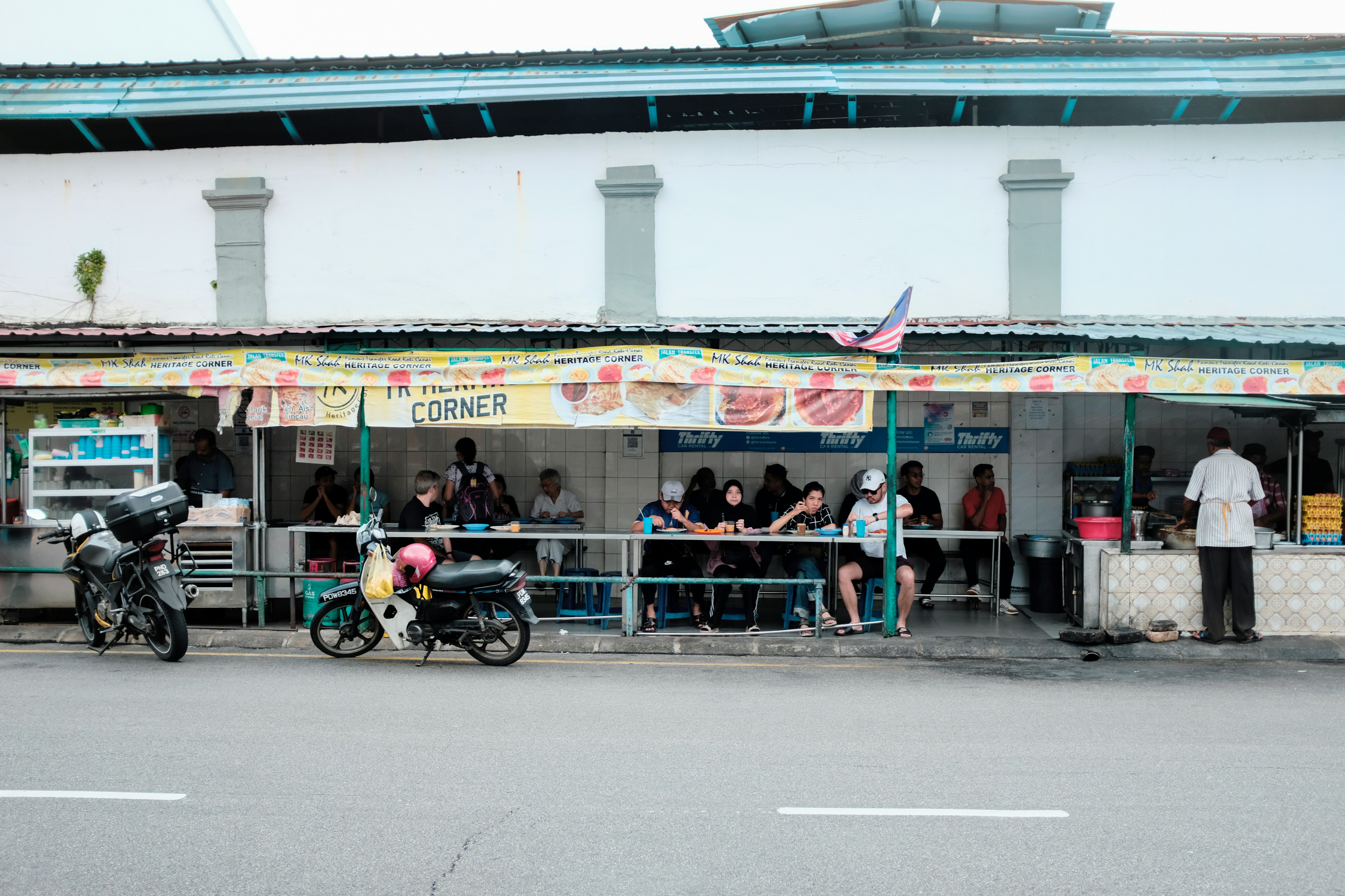 A group of people standing outside of a food stand