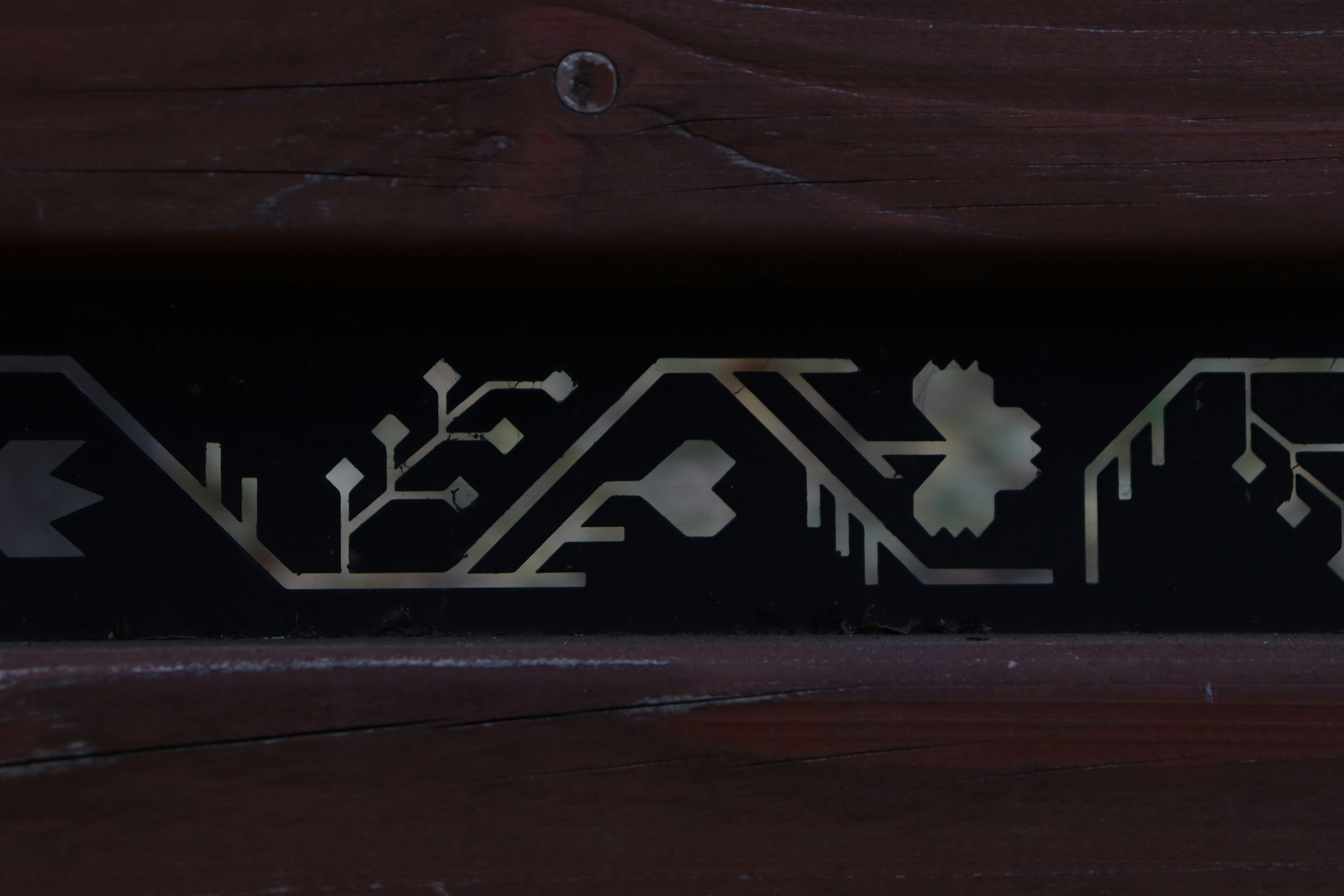 A close up of a wooden bench with metal lettering