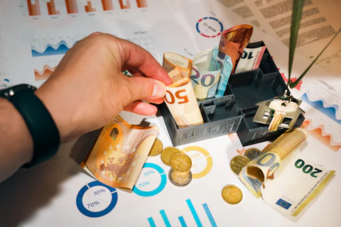 A person putting money into a miniature model house