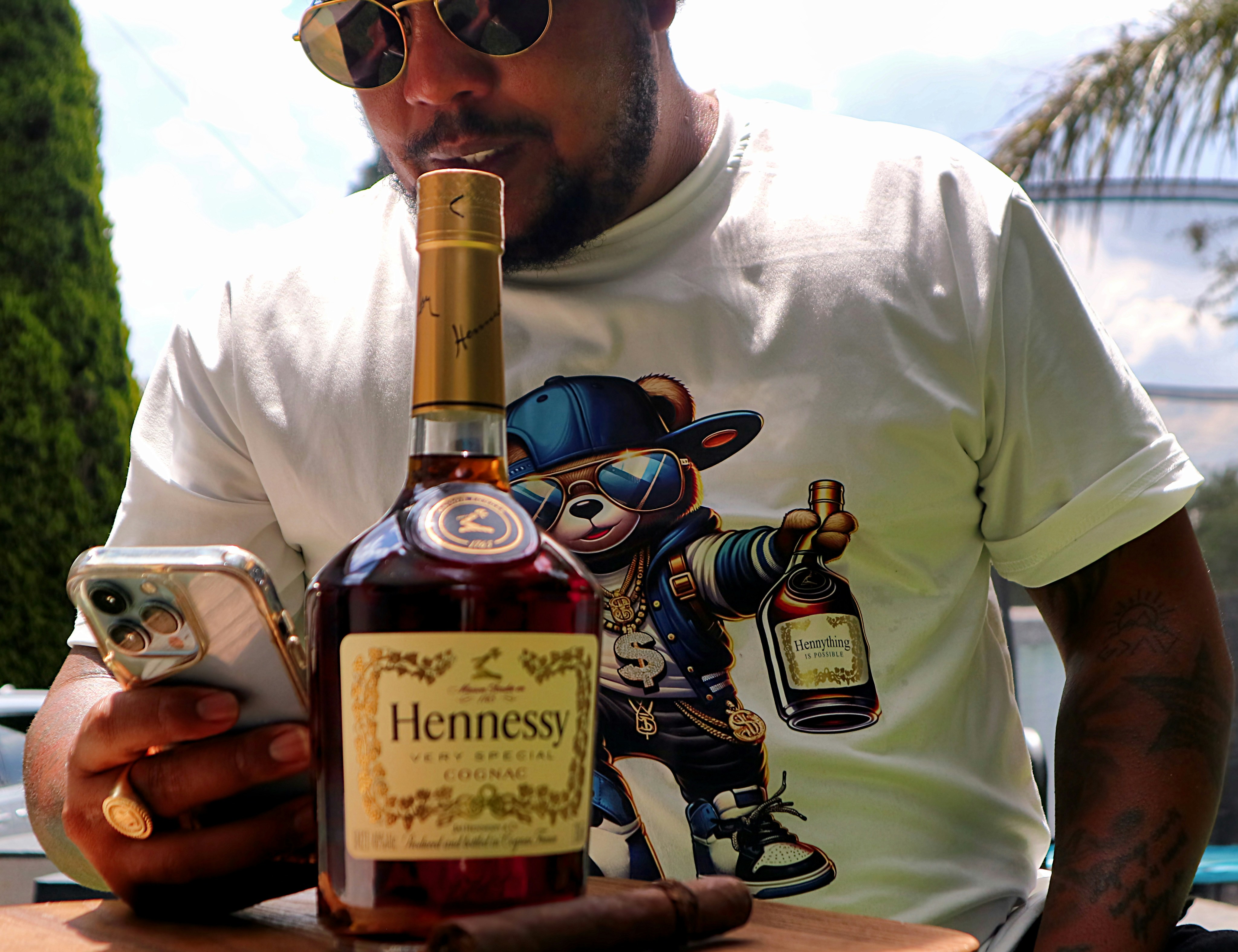 A man holding a bottle of liquor and a cell phone