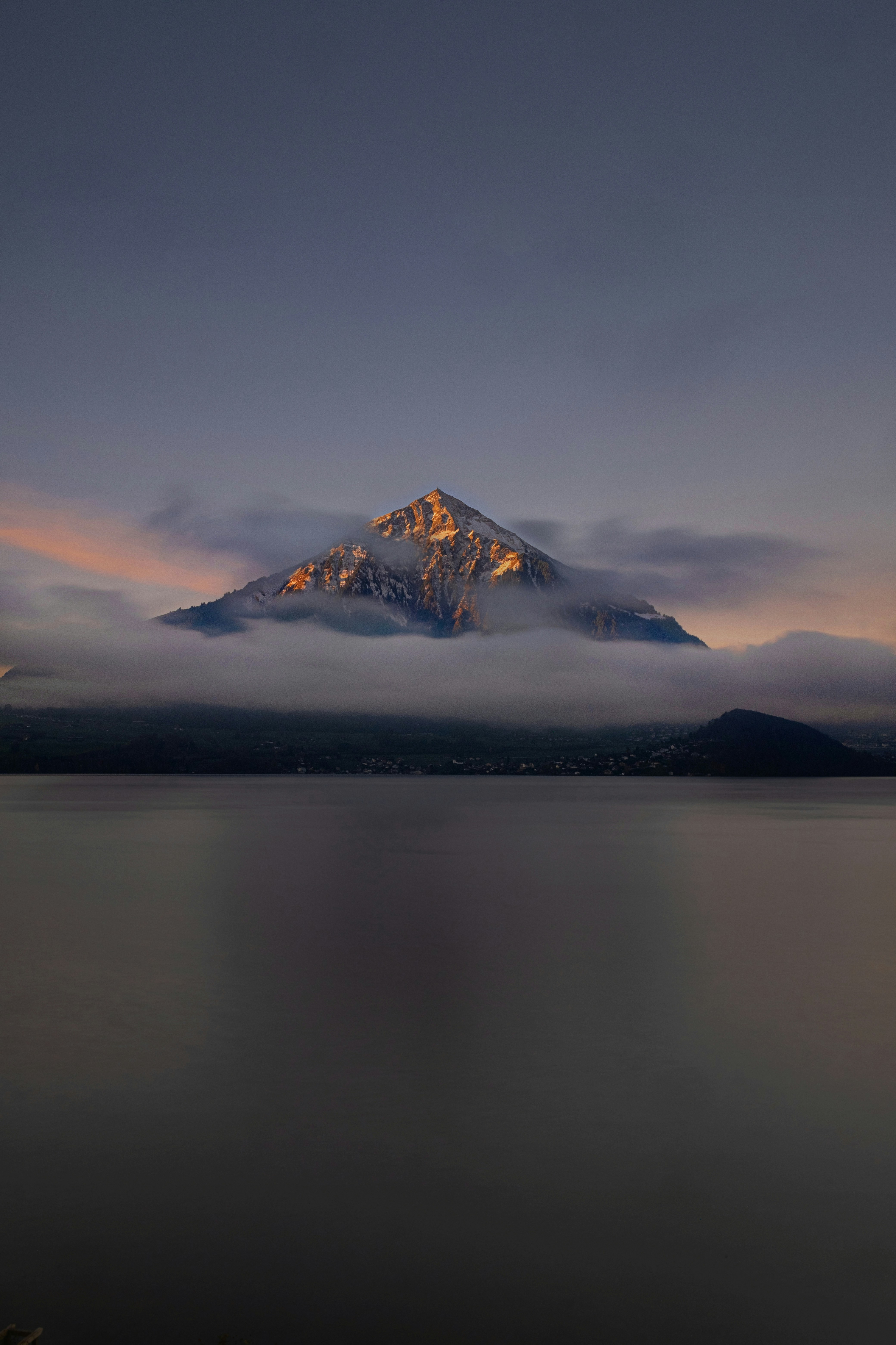 Une montagne couverte de nuages et un plan d’eau