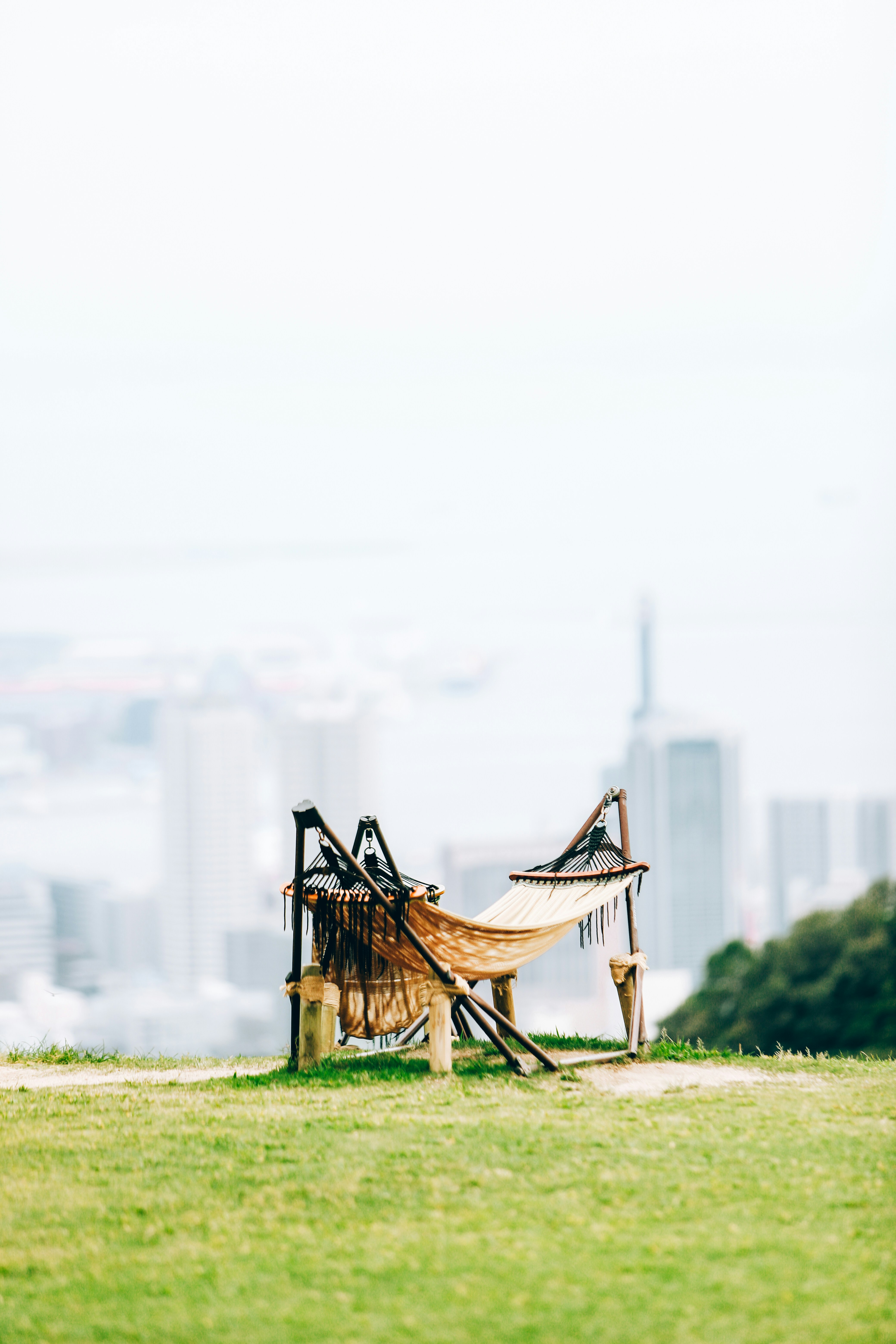 A hammock set up on a grassy hill overlooking a city