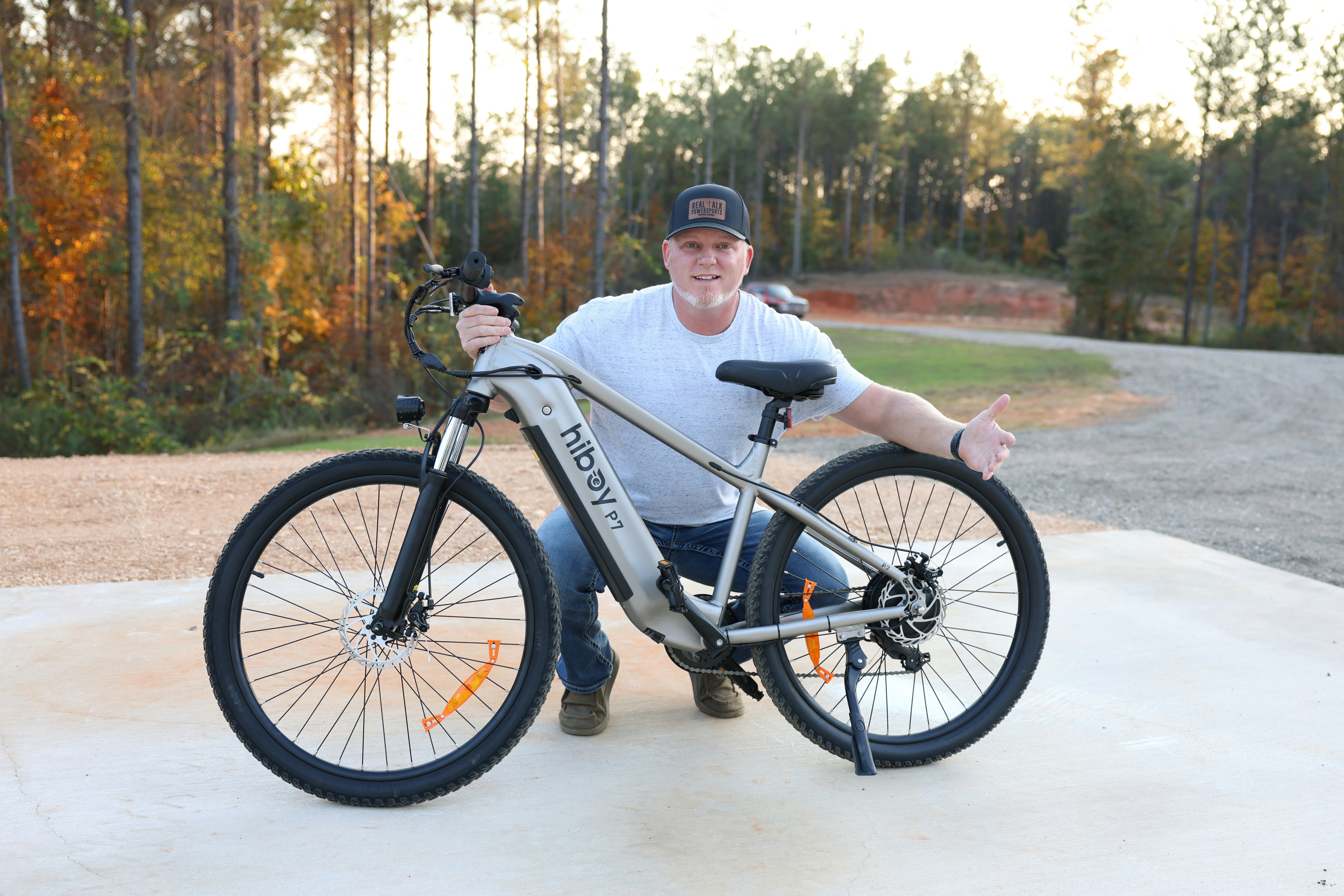 A man standing next to a bike in a parking lot