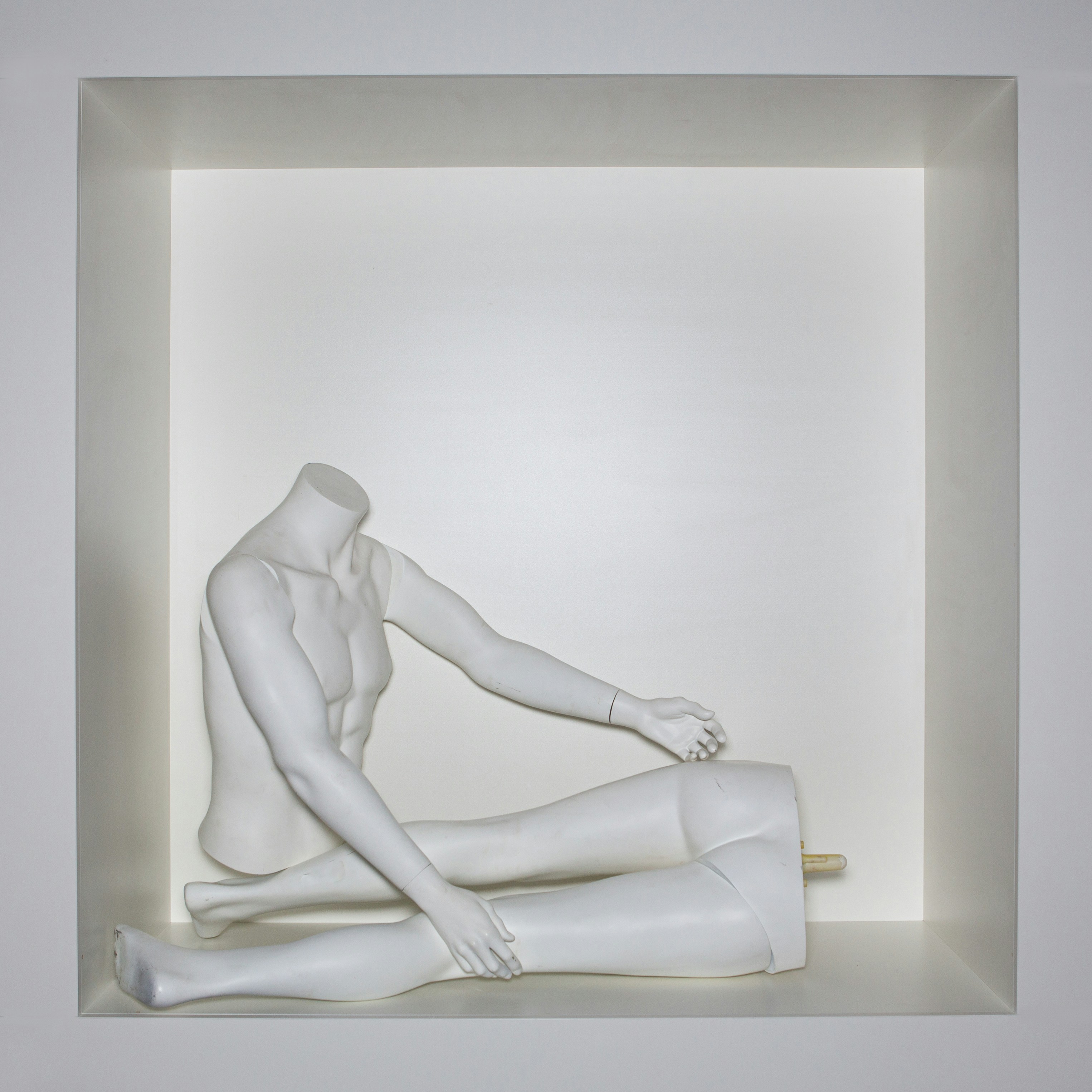 A white mannequin sitting in a white box