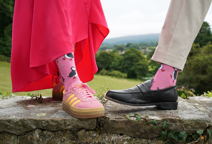 Close detail of two people wearing soft pink patterned dress socks
