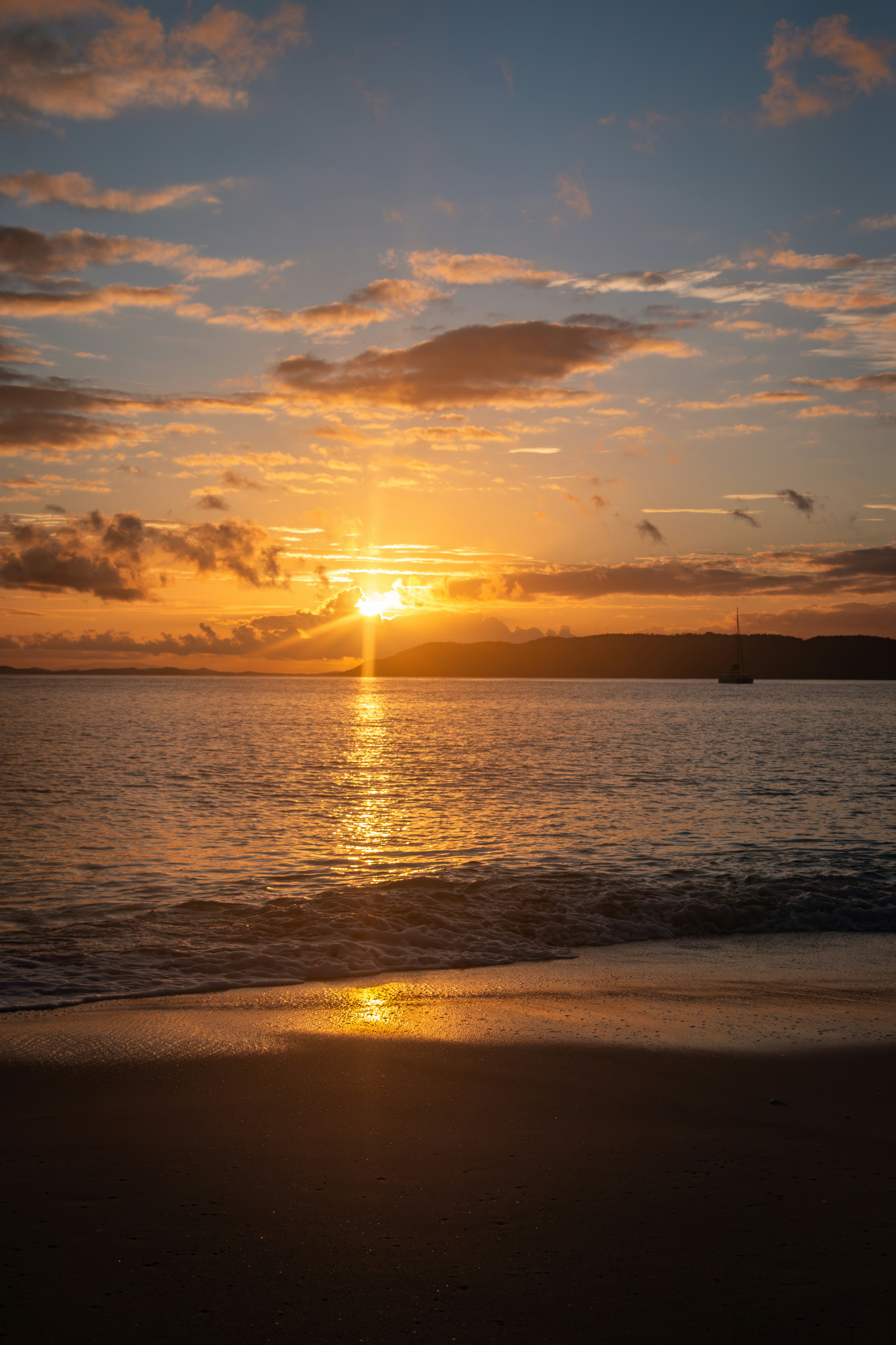 The sun is setting over the water on the beach
