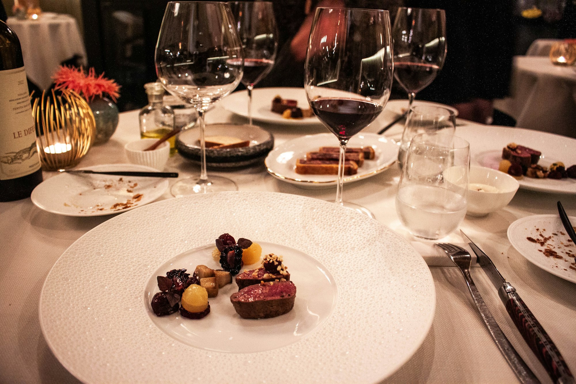 Elegant table set with fine wine glasses and beautifully plated Michelin-level dishes