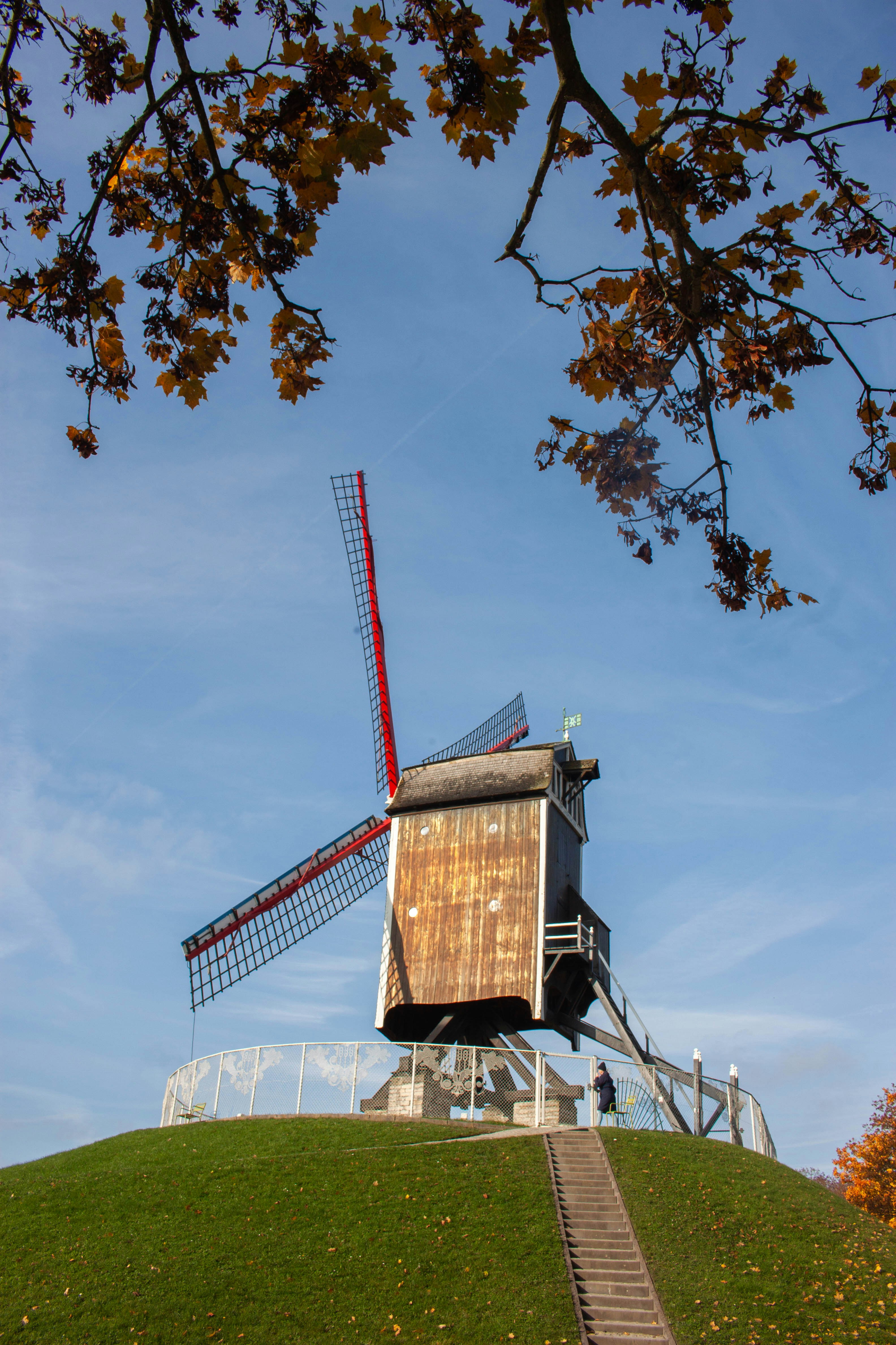 A windmill sitting on top of a lush green hillside