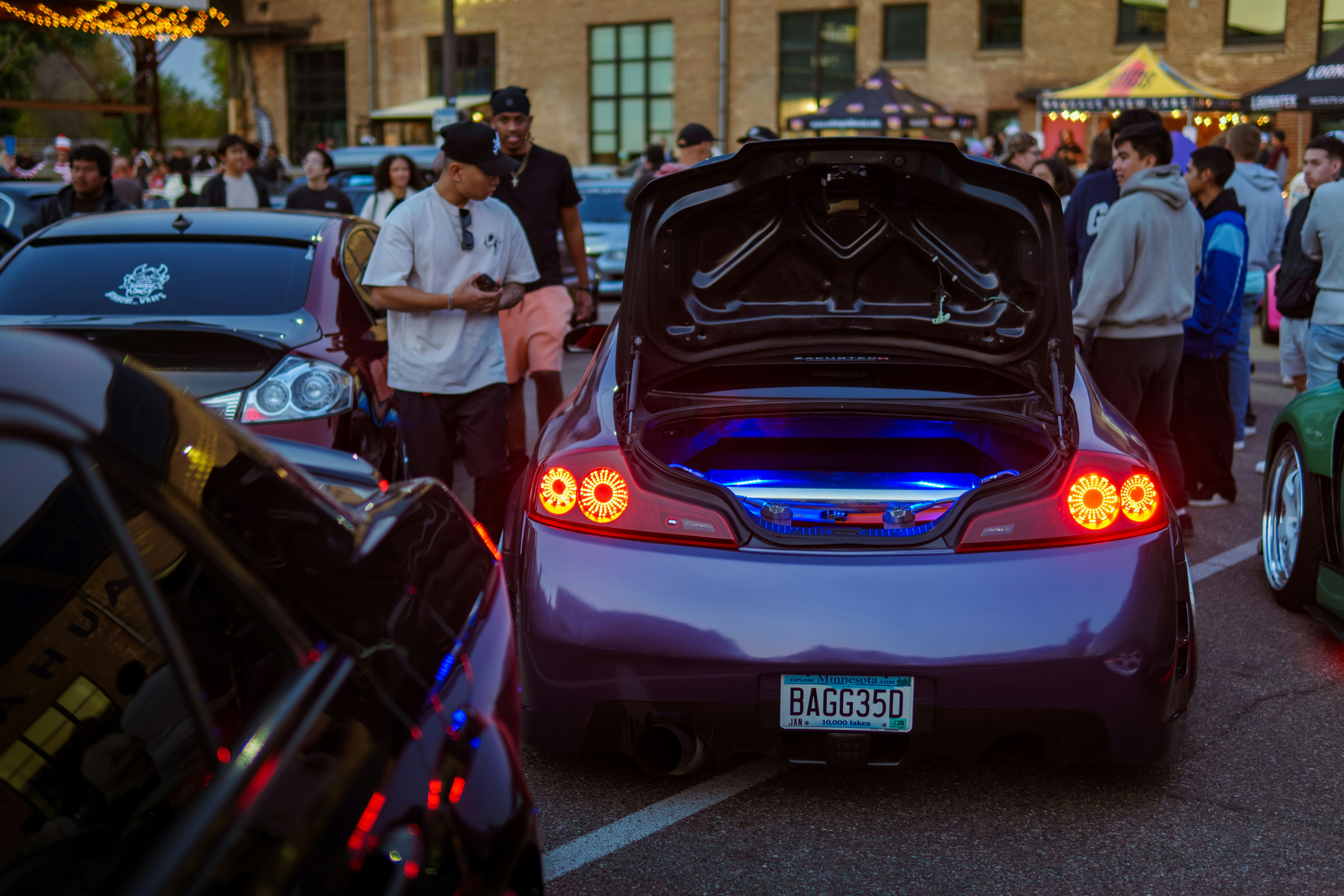 A group of people standing around a car with its trunk open
