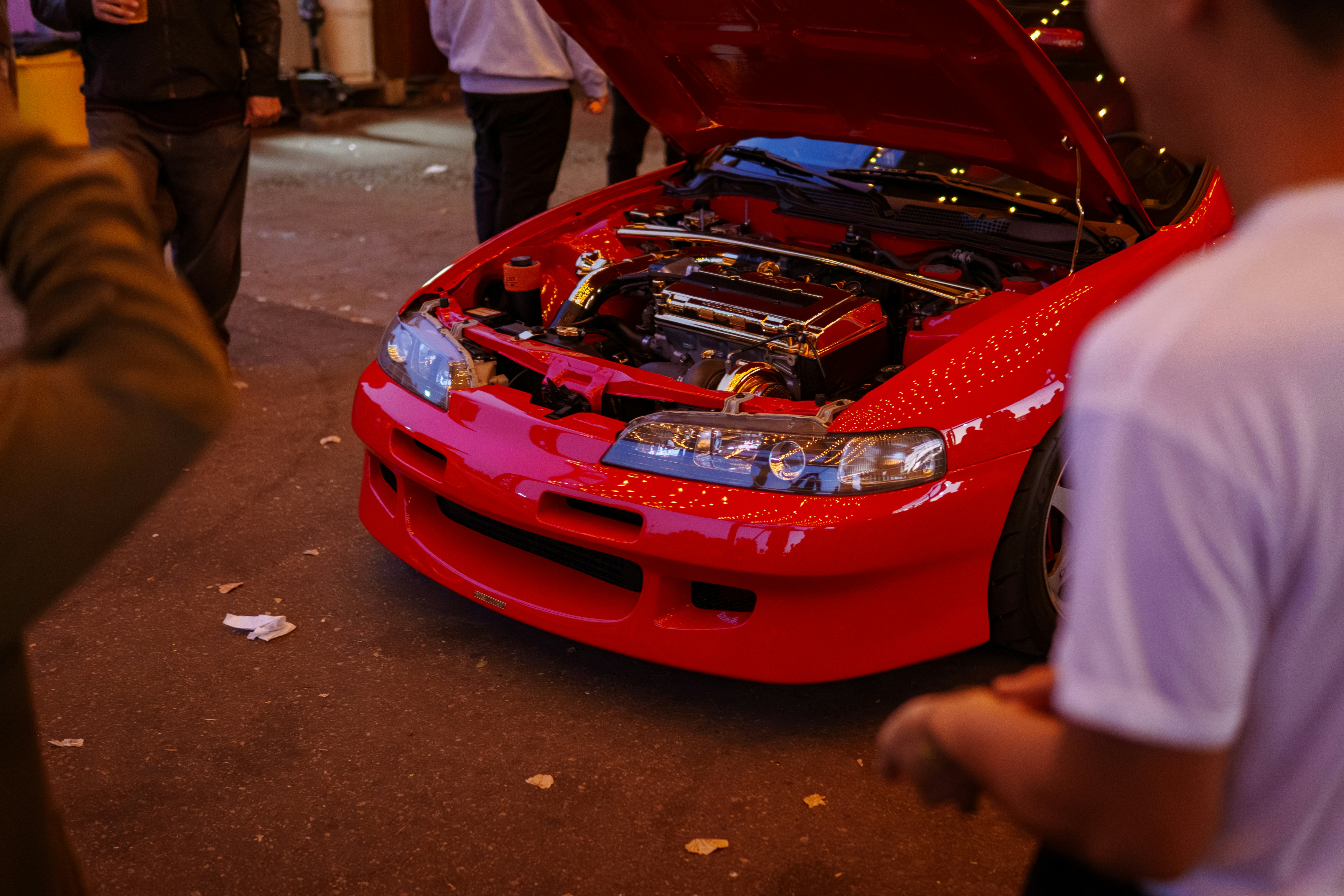 A red car with its hood open on a street
