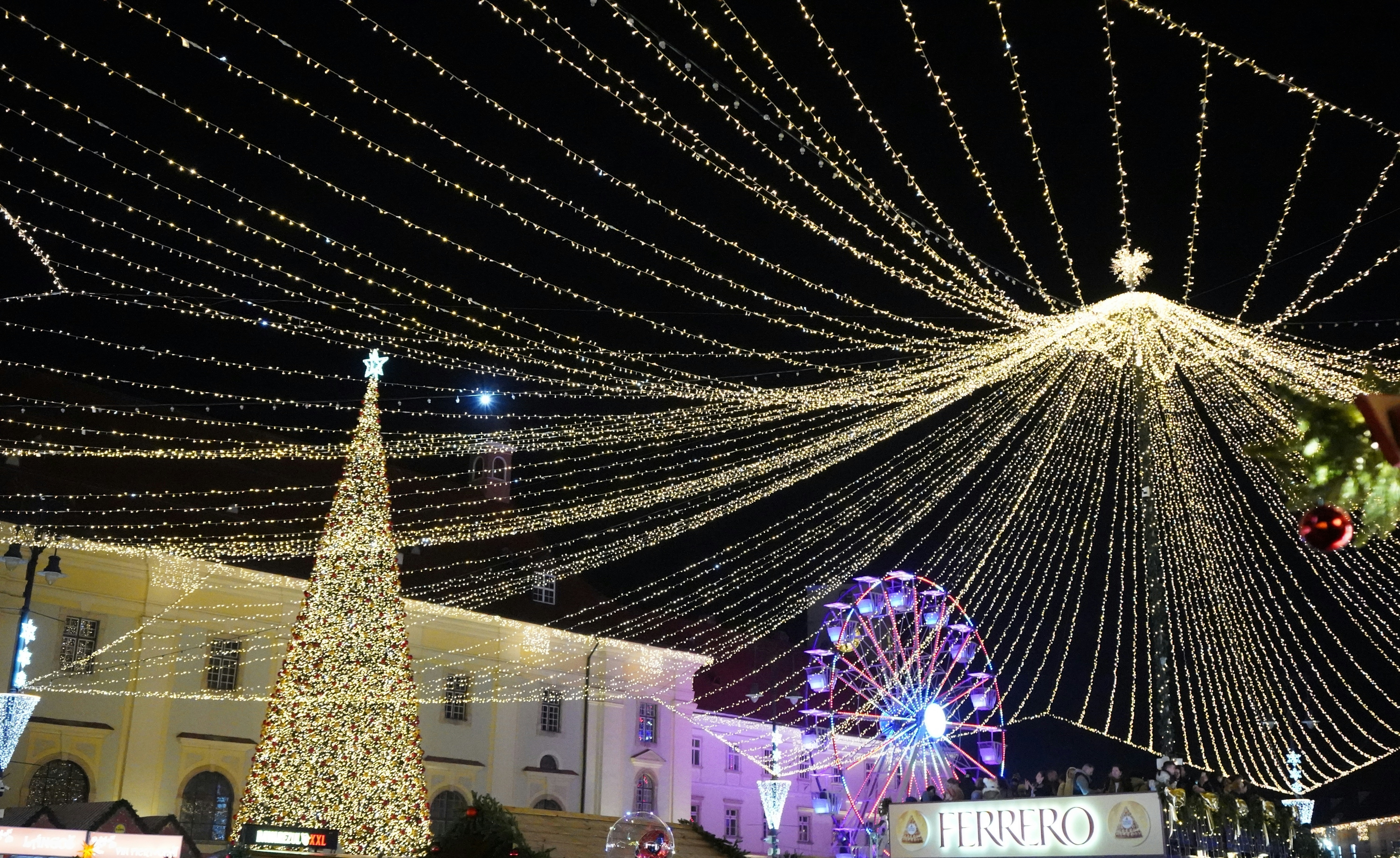 A large christmas tree is lit up in the middle of the street
