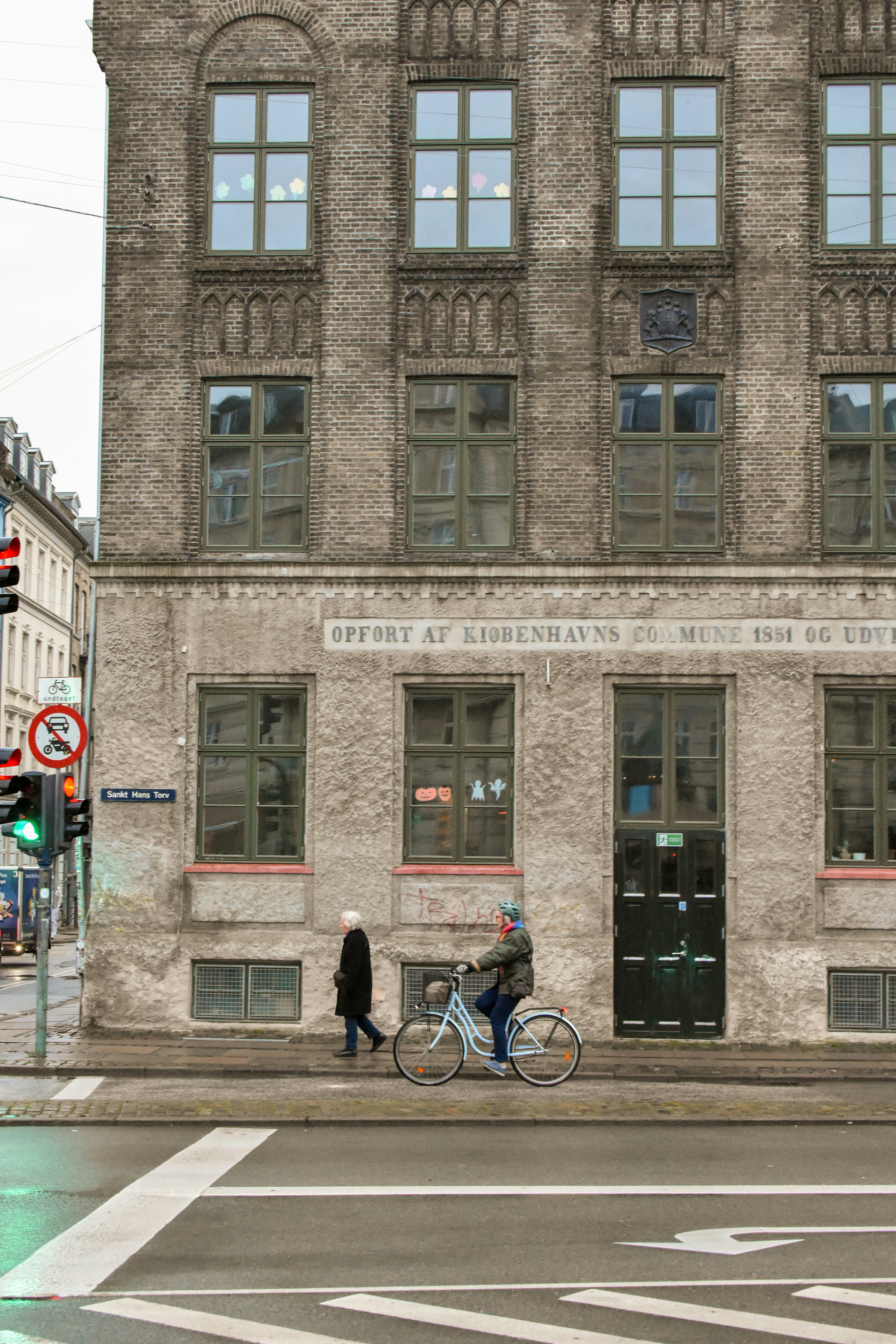 A man riding a bike down a street next to a tall building