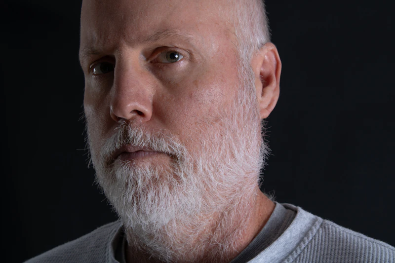 gentle older man with a white beard and gray sweater
