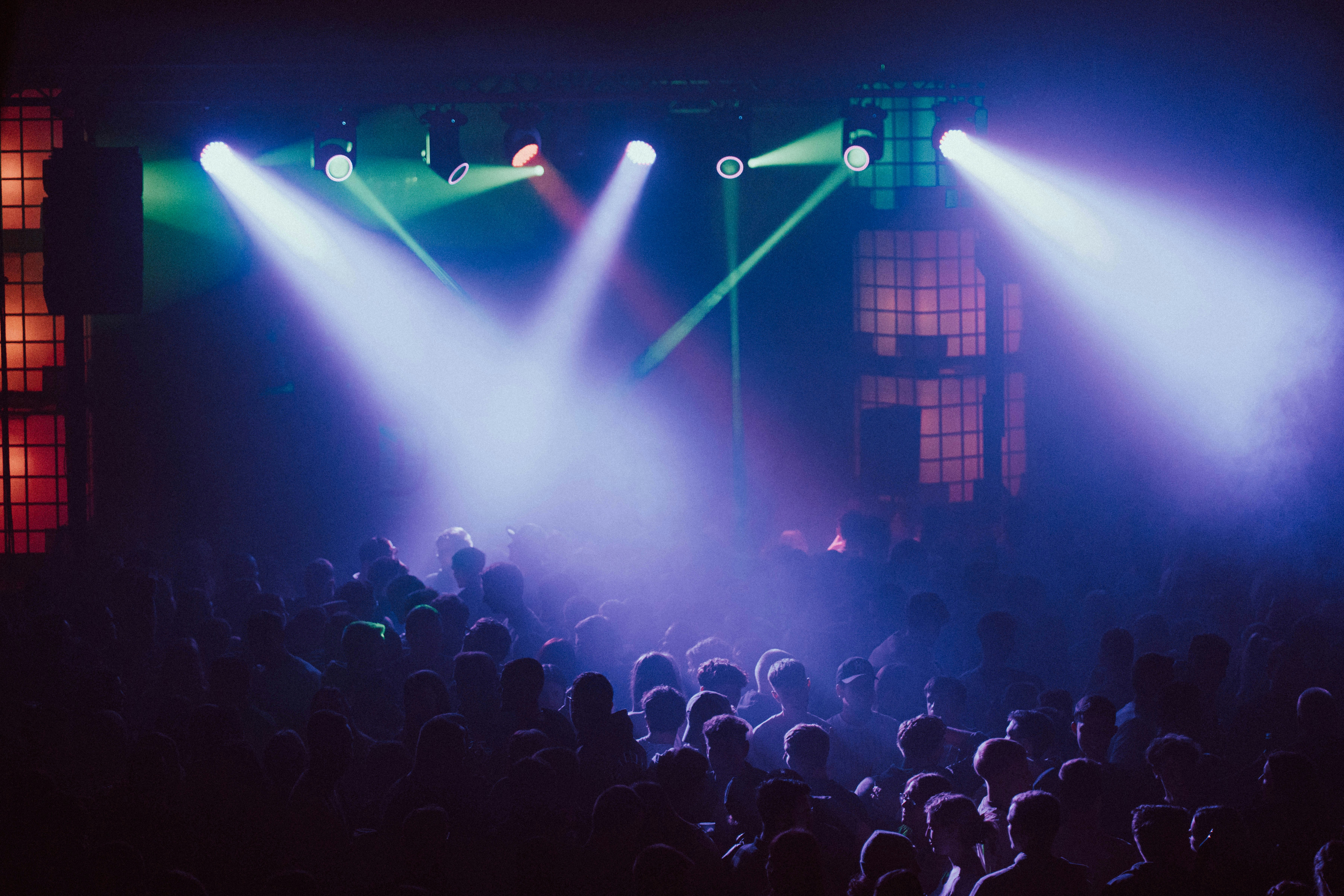 A crowd of people in front of a stage with lights