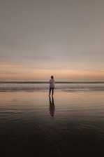 A person standing on a beach at sunset