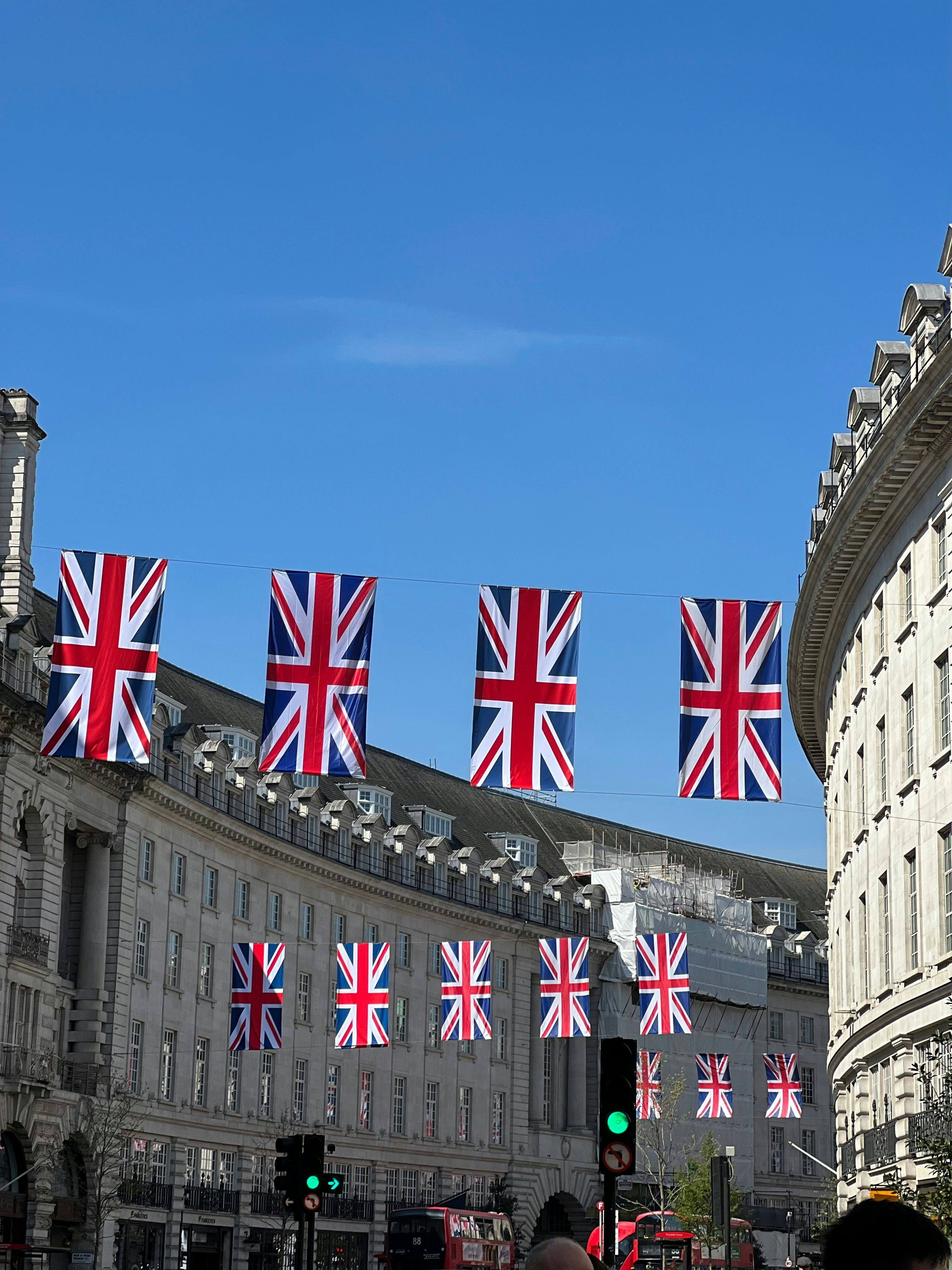 Windsor Castle exterior on a bright sunny day, Union Jack flying, manicured grounds, blue sky, classic British royal architecture