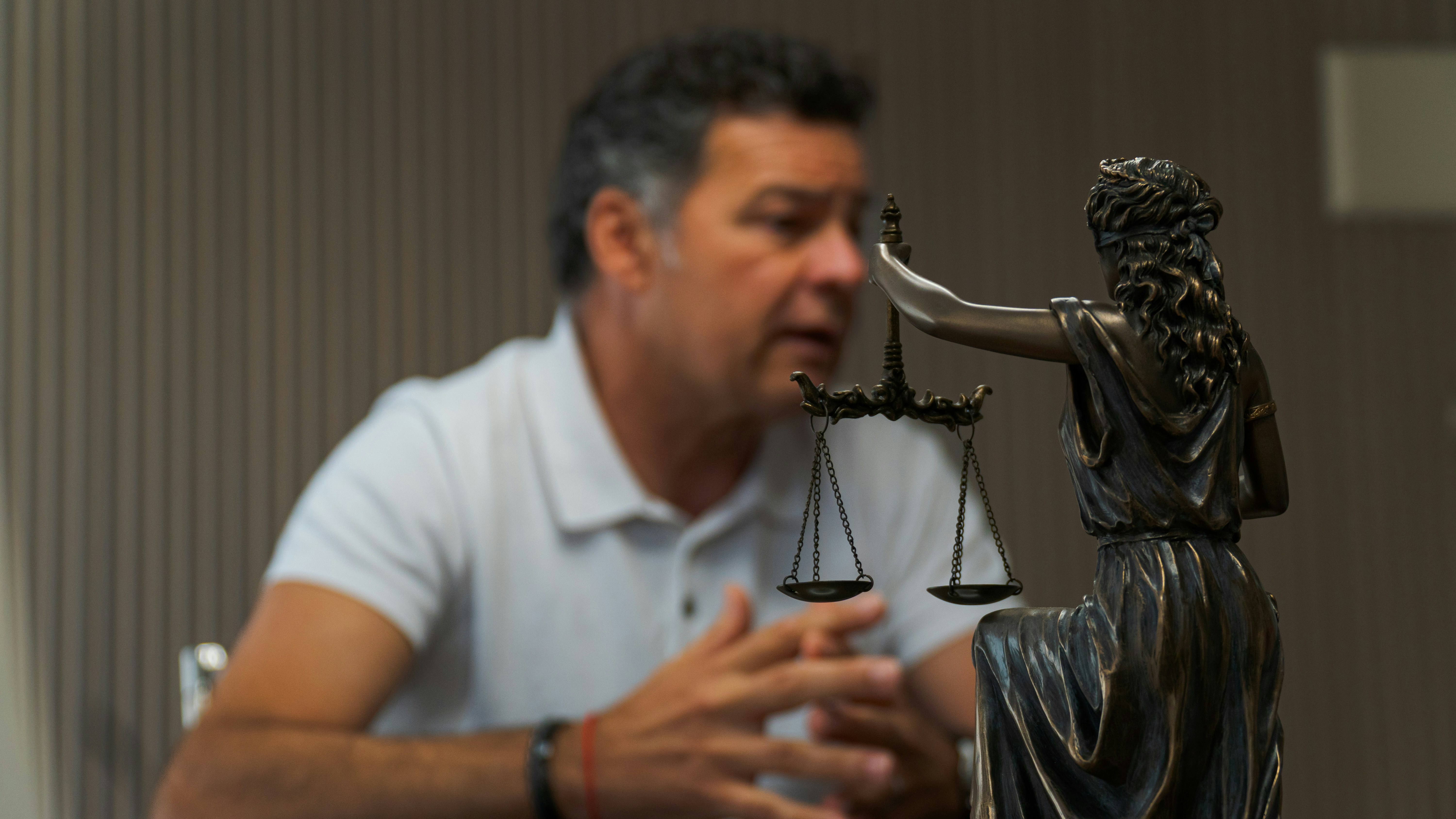 A man sitting at a table in front of a statue.
