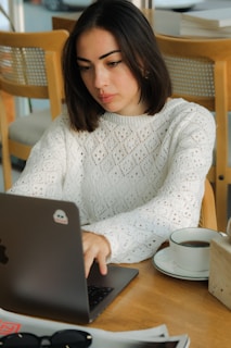 A woman sitting at a table using a laptop computer