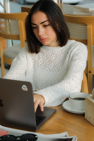 A woman sitting at a table using a laptop computer