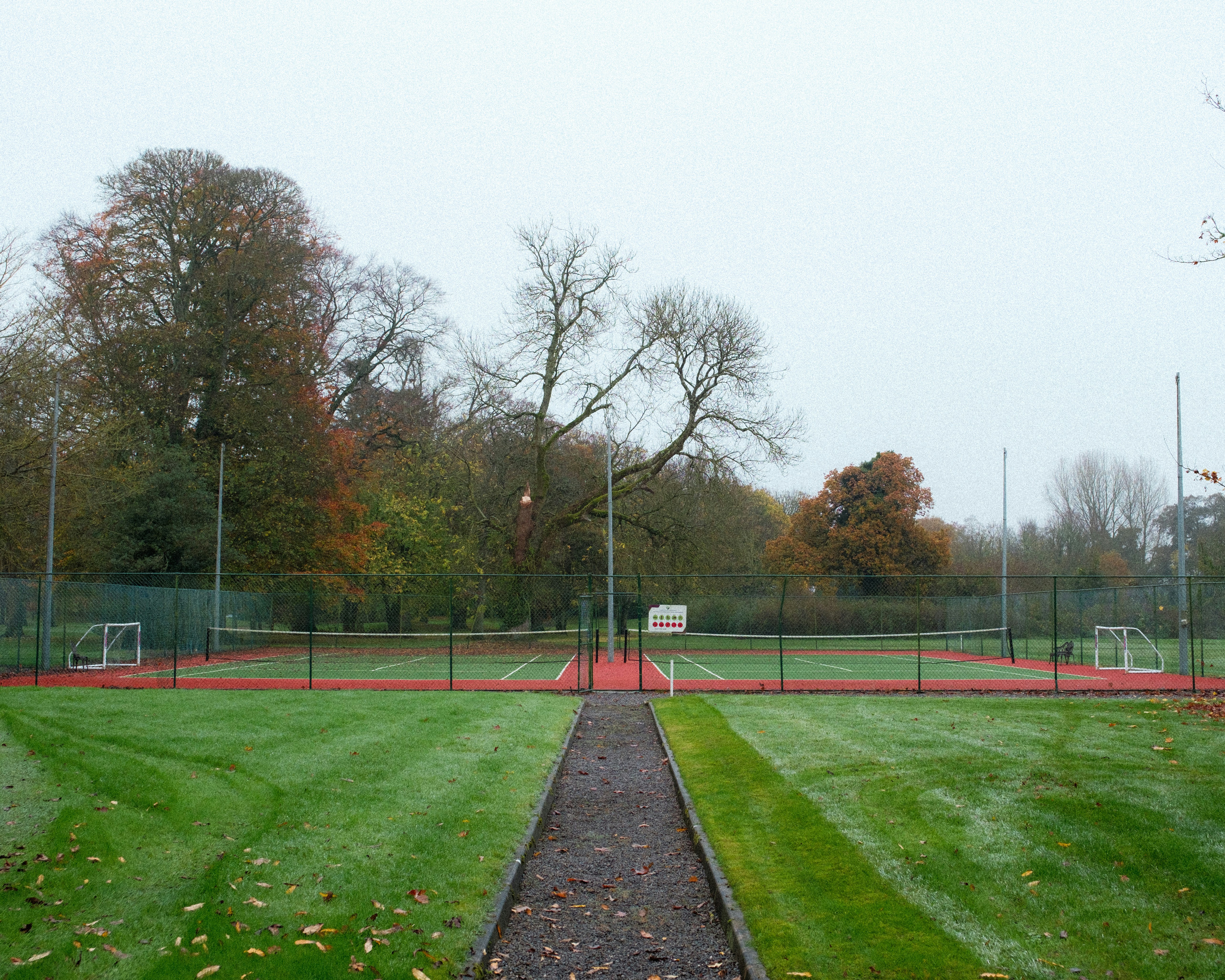 A grassy field with a basketball court in the background