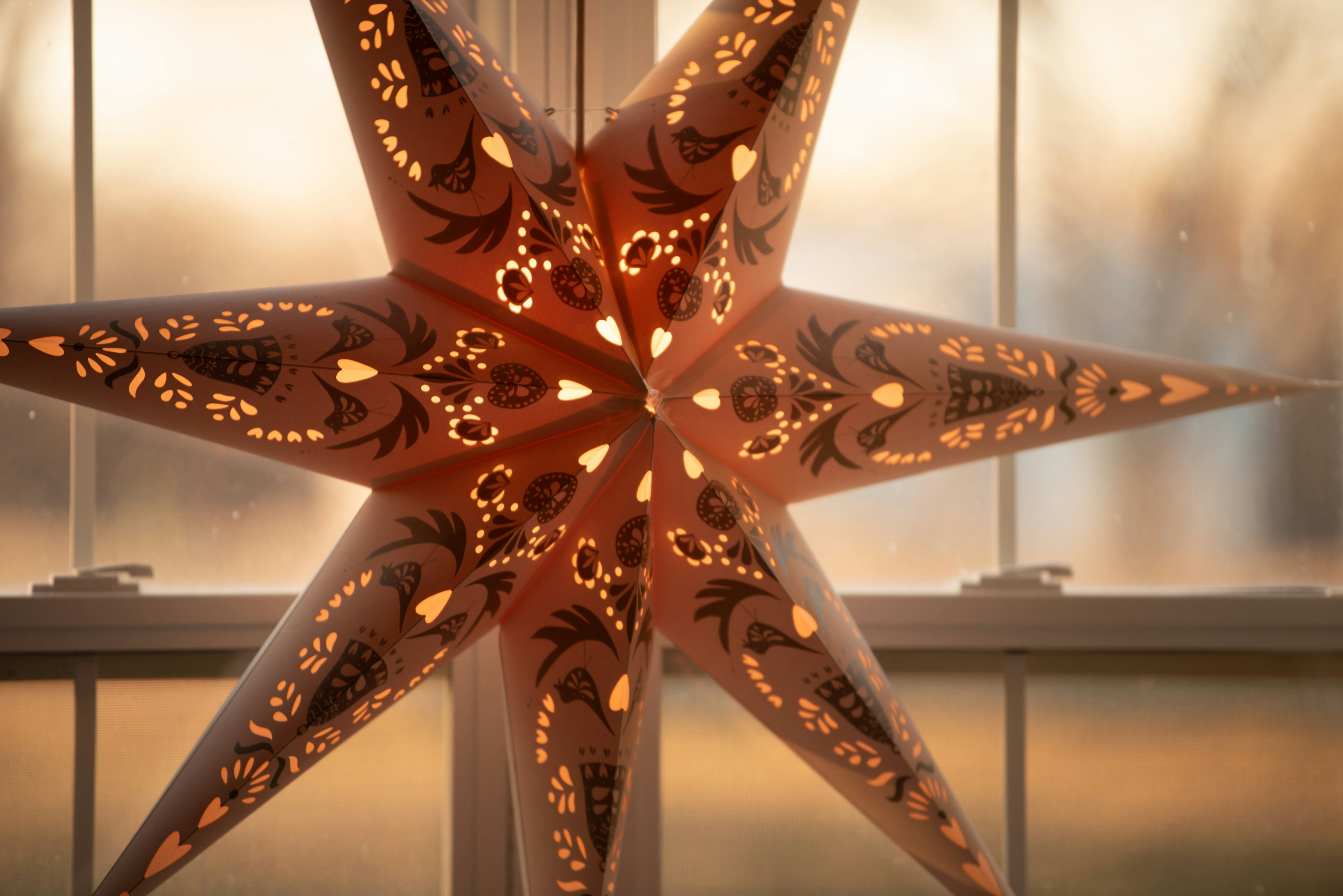 A lighted star sitting in front of a window