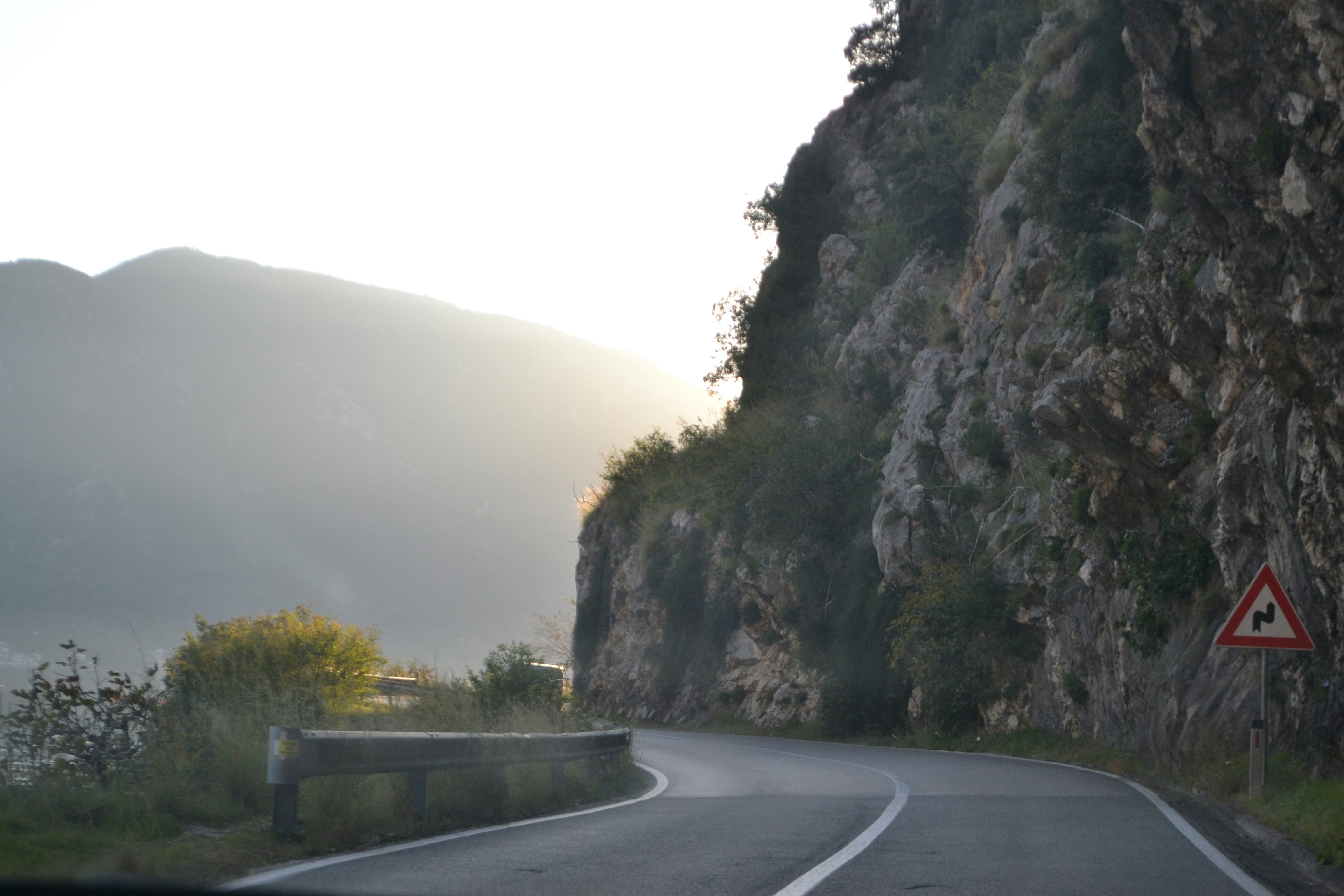A car driving down a mountain road next to a cliff