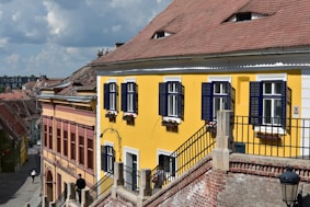 A yellow building with blue shutters on a cloudy day