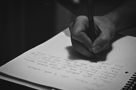 A person writing on a notebook with a pen