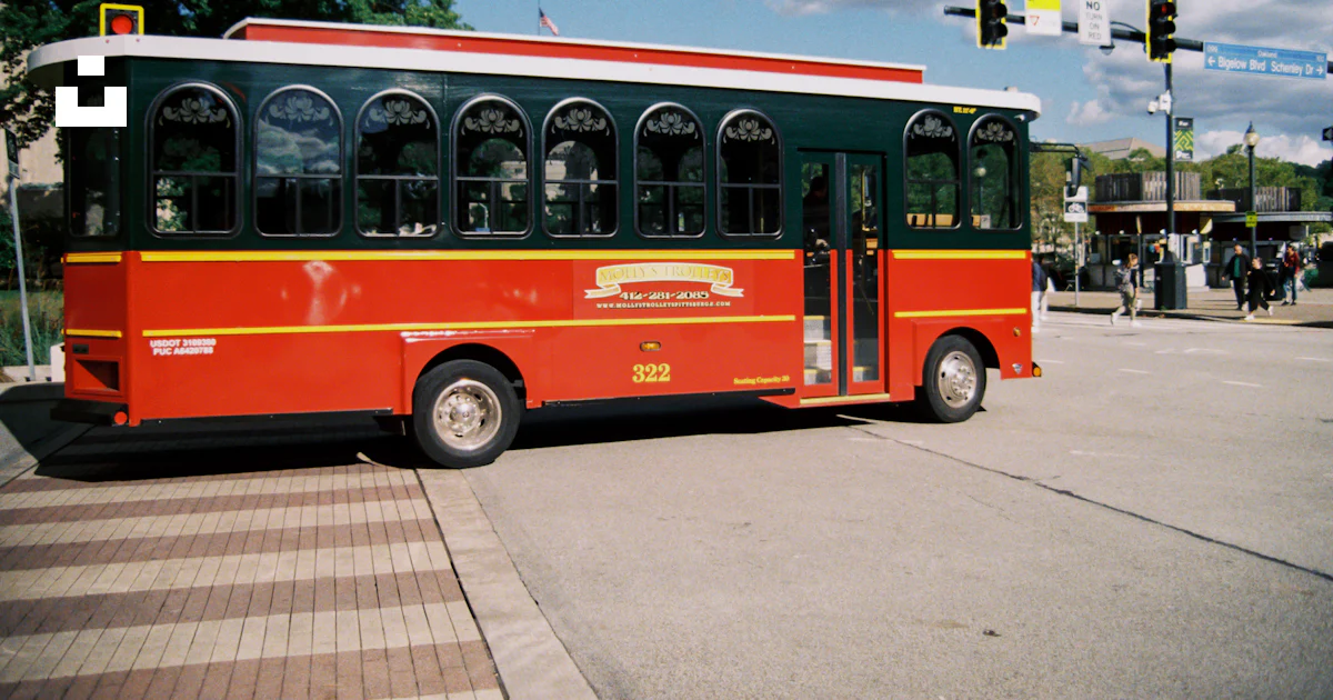 A red and black bus parked on the side of the road photo – Free ...