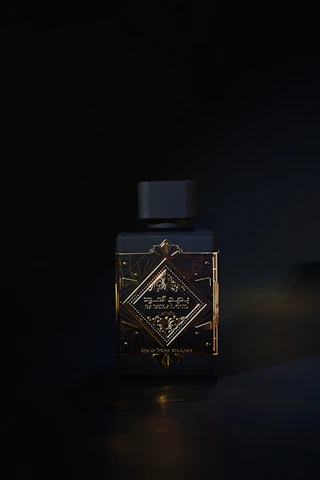 A bottle of perfume sitting on a table in the dark