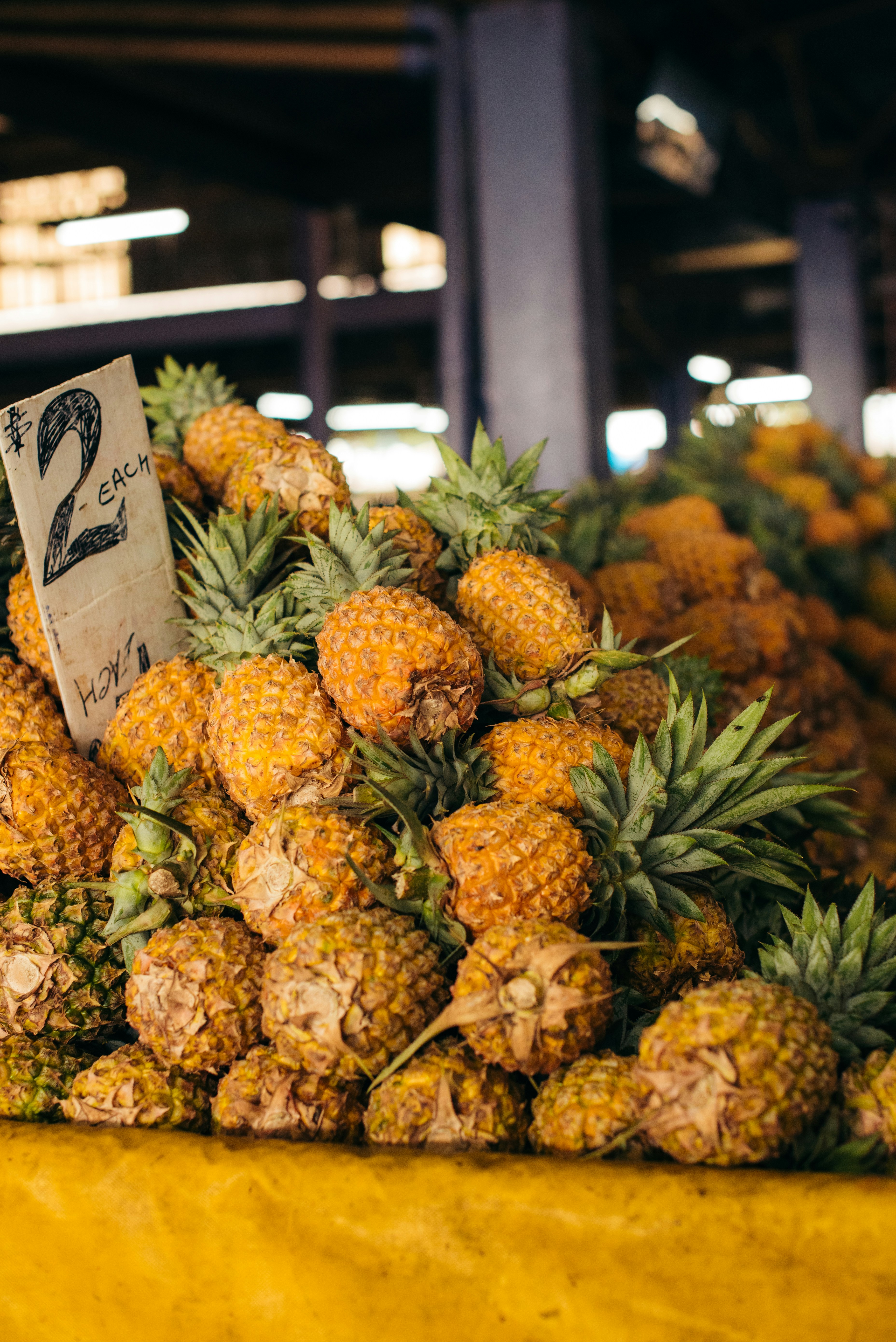 A pile of pineapples sitting on top of a yellow table