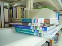 A stack of books sitting on top of a white shelf