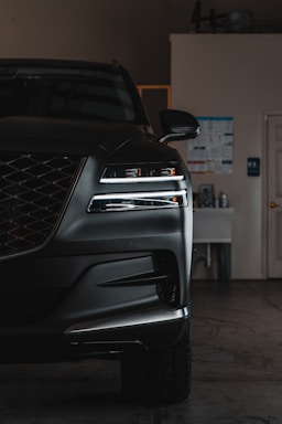 A black car parked in a garage next to a white door