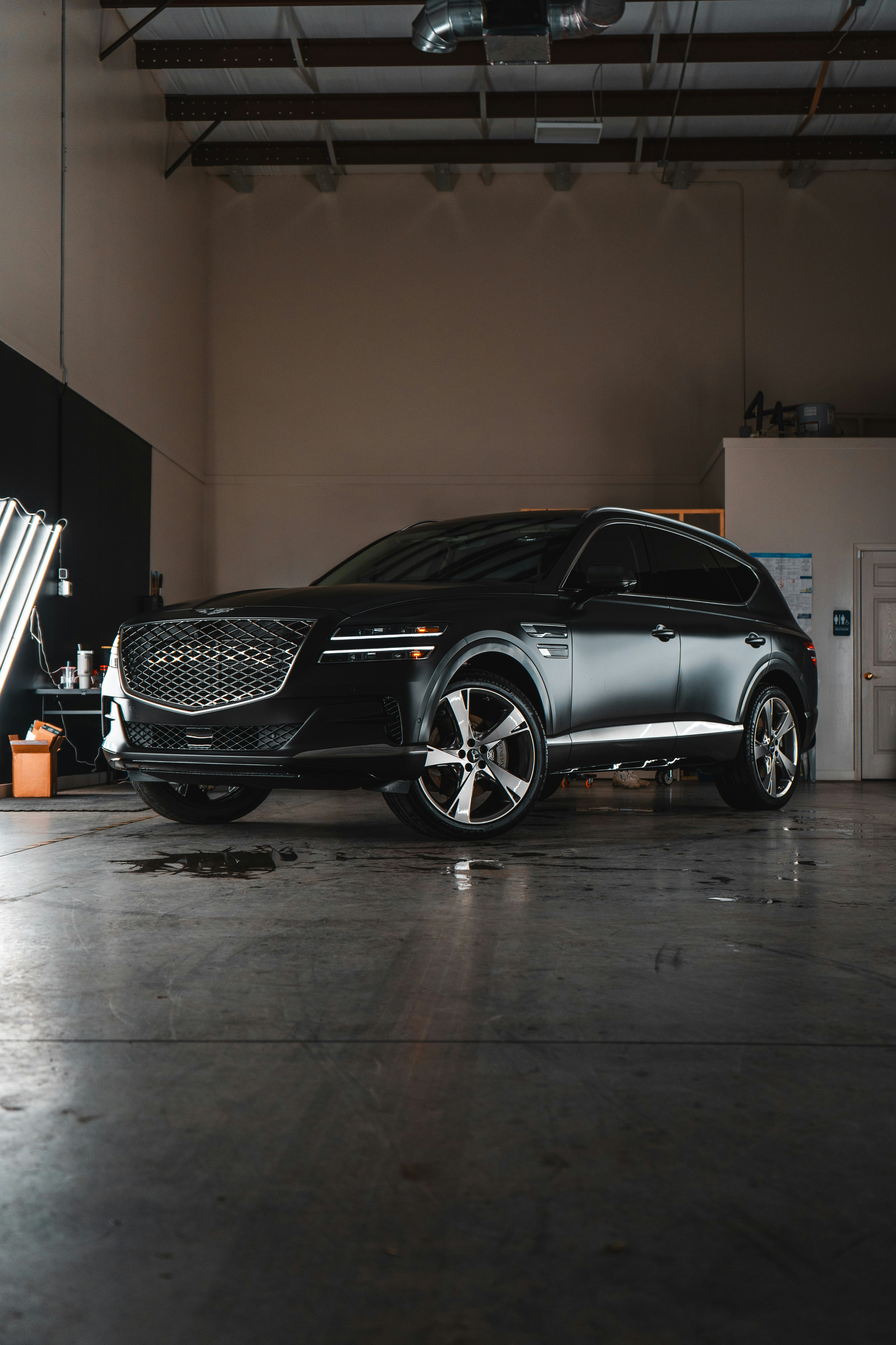 A black car parked in a garage next to another car