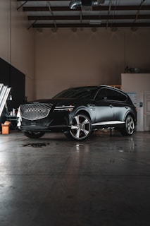 A black car parked in a garage next to another car