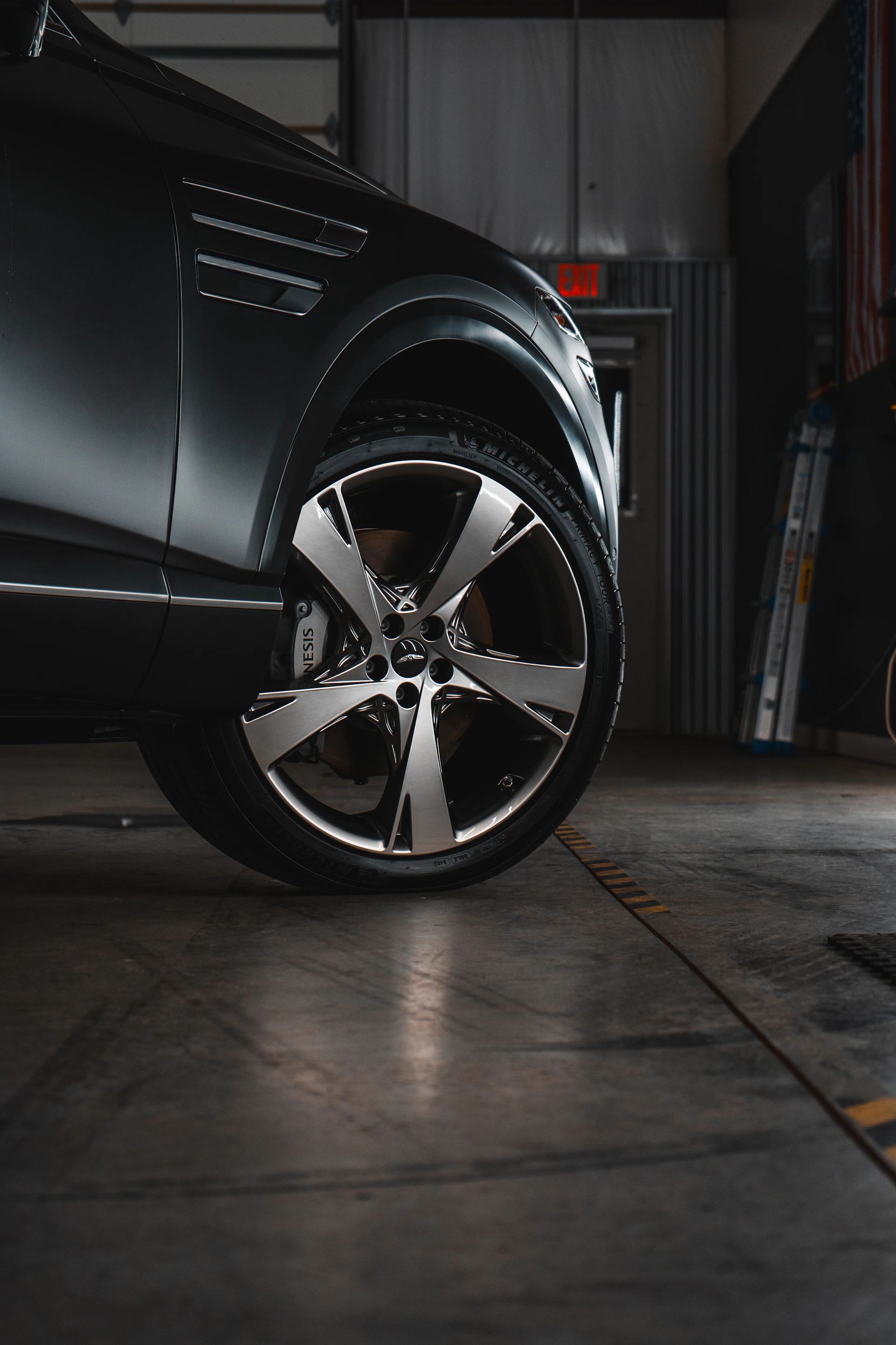 A black car parked in a garage next to another car