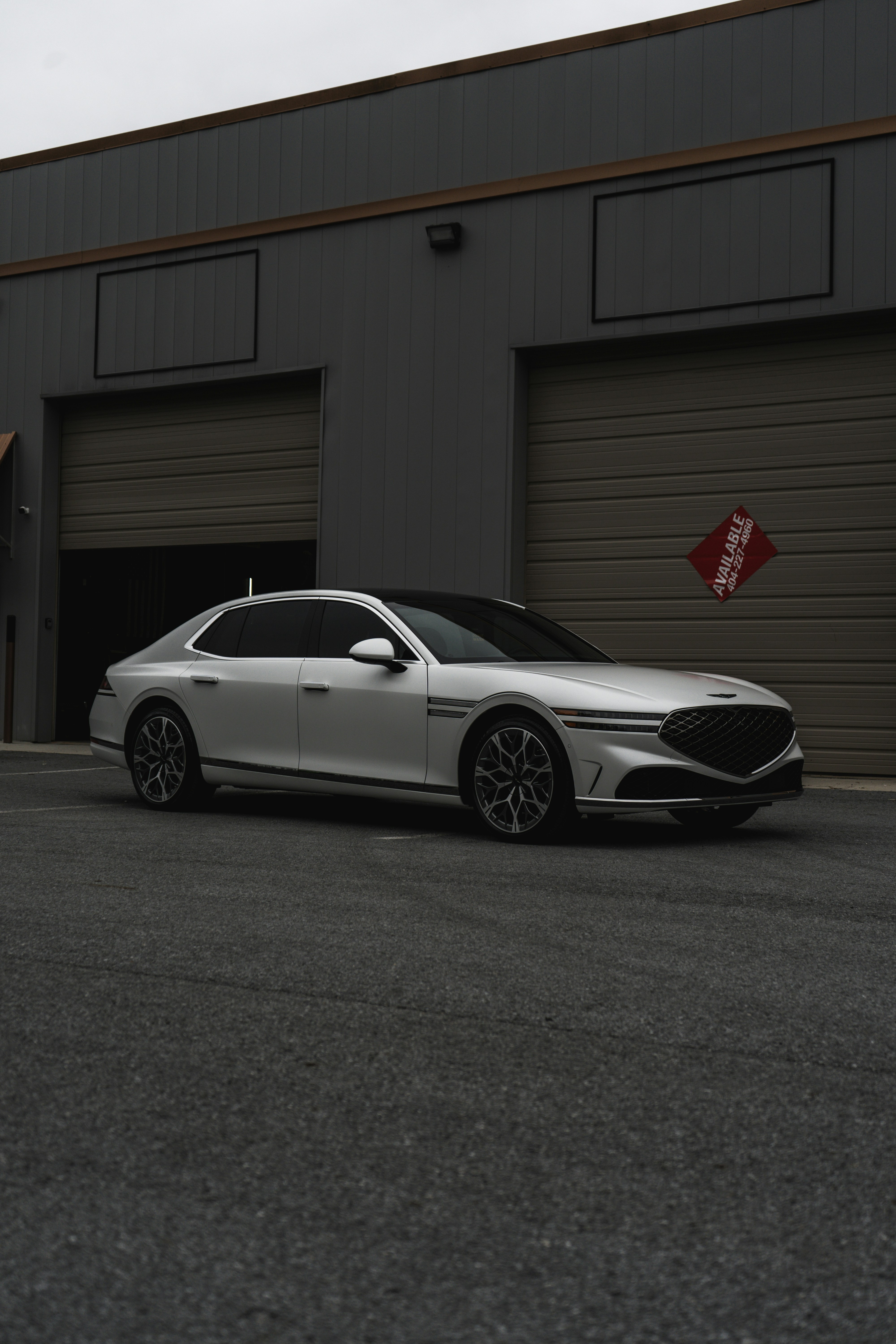 White luxury sedan parked in front of a commercial building.