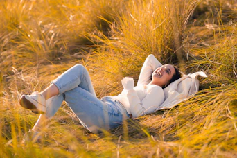 A woman laying in a field of tall grass