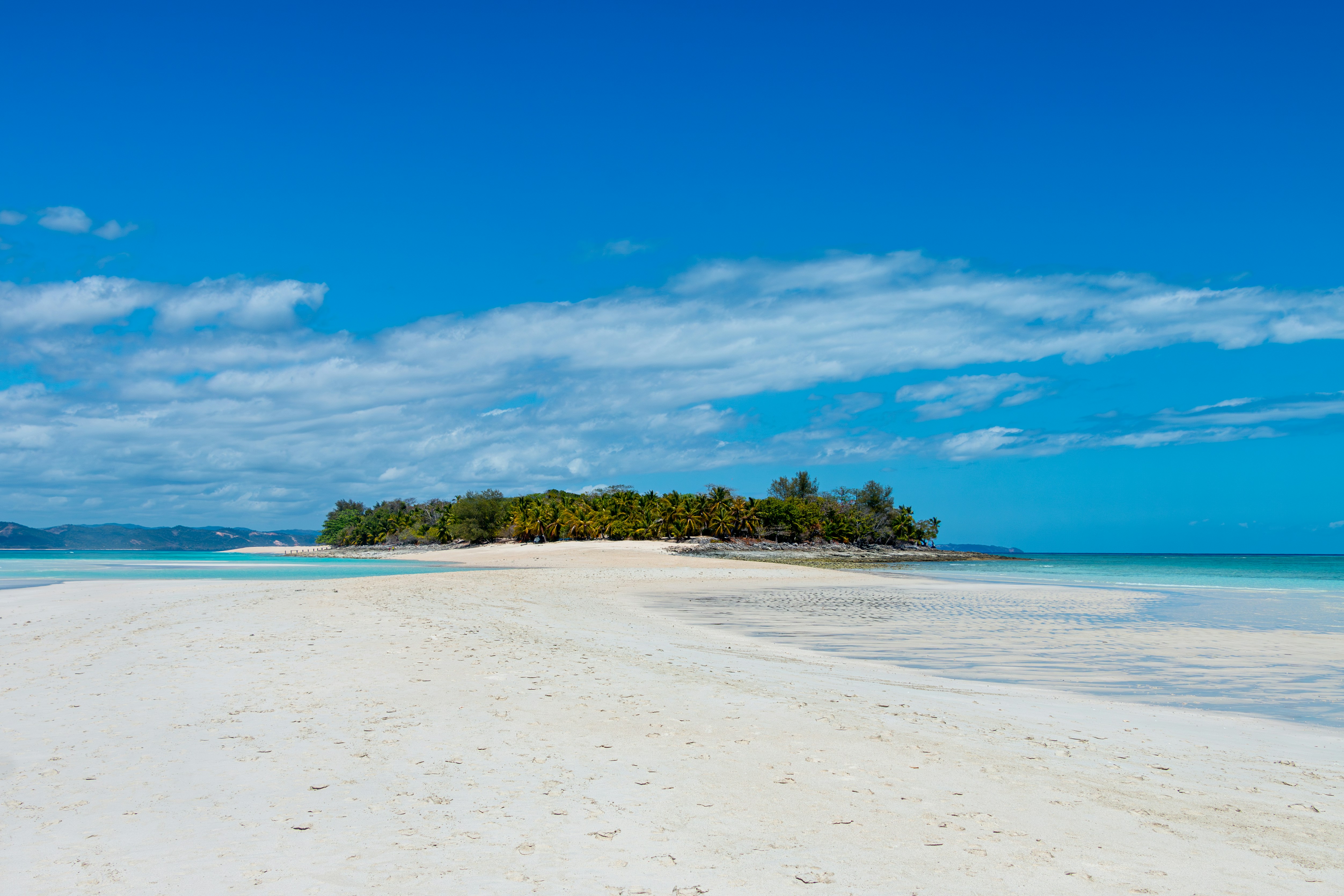 A sandy beach with a small island in the distance