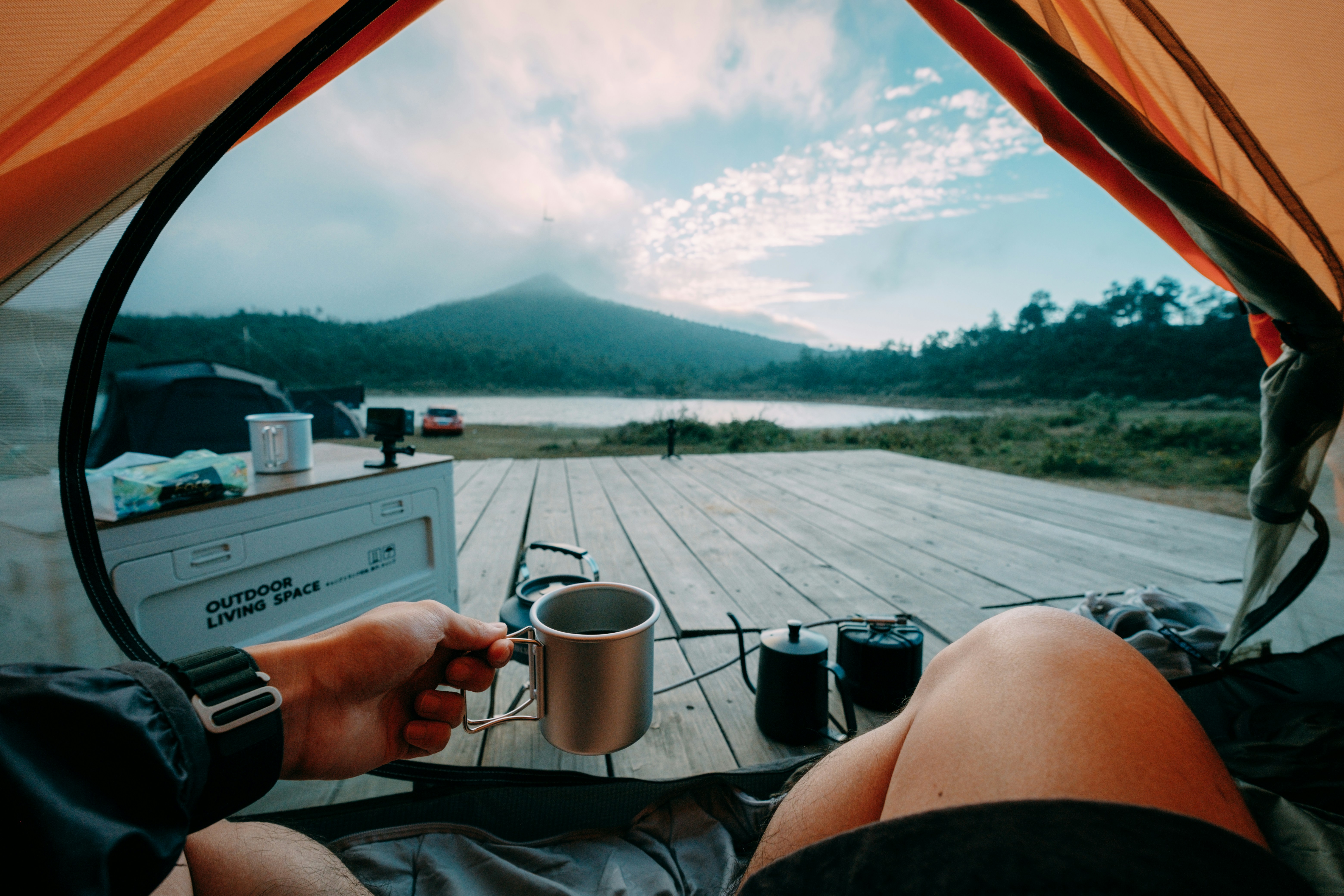A person sitting in a tent with a cup of coffee
