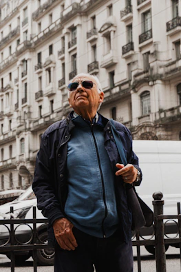 A man standing in front of a fence in a city