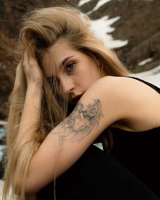 A woman with a tattoo on her arm sitting in the snow