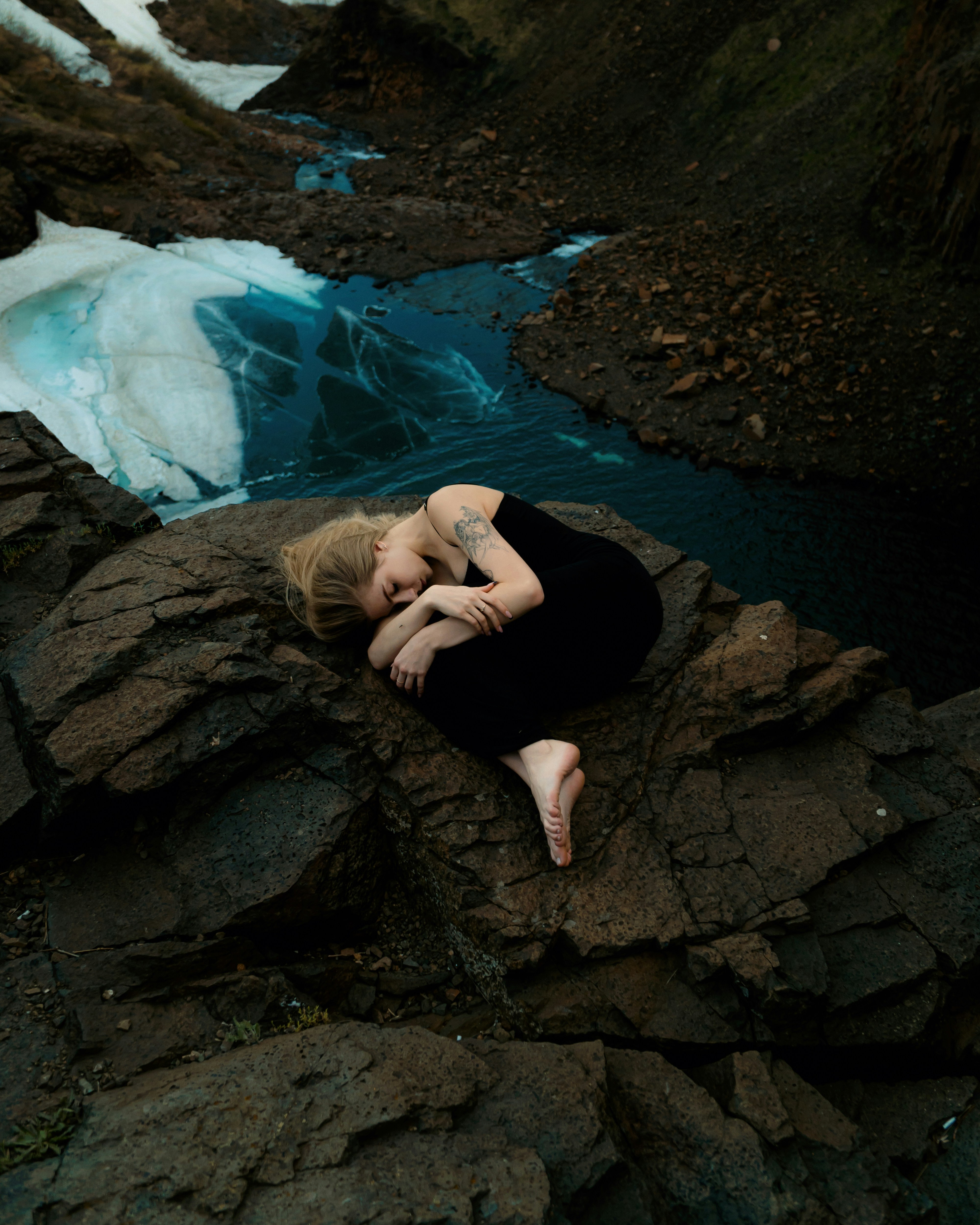A woman laying on a rock next to a river
