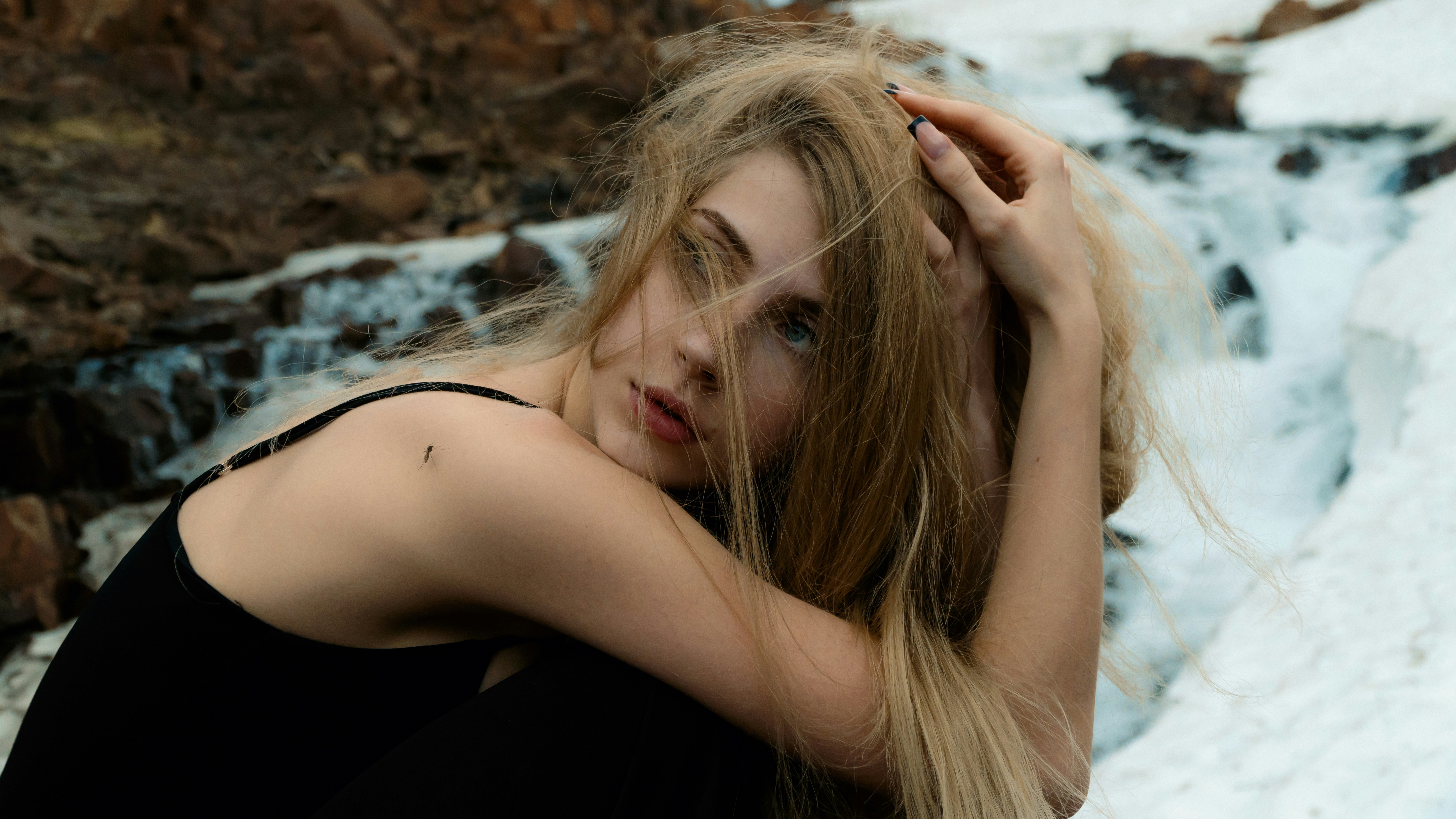 A woman with long hair standing in front of a waterfall