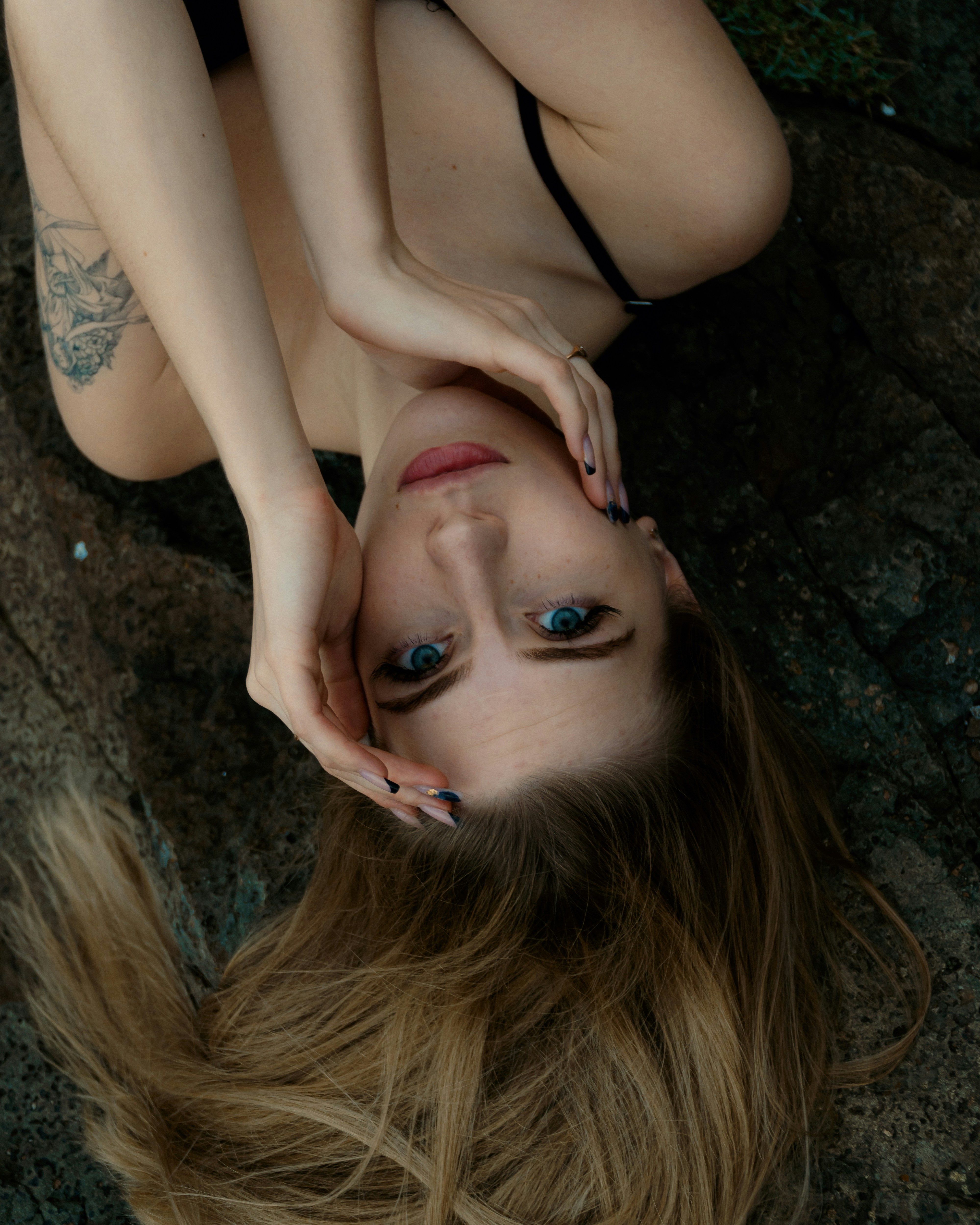 A woman laying on the ground with her hair blowing in the wind