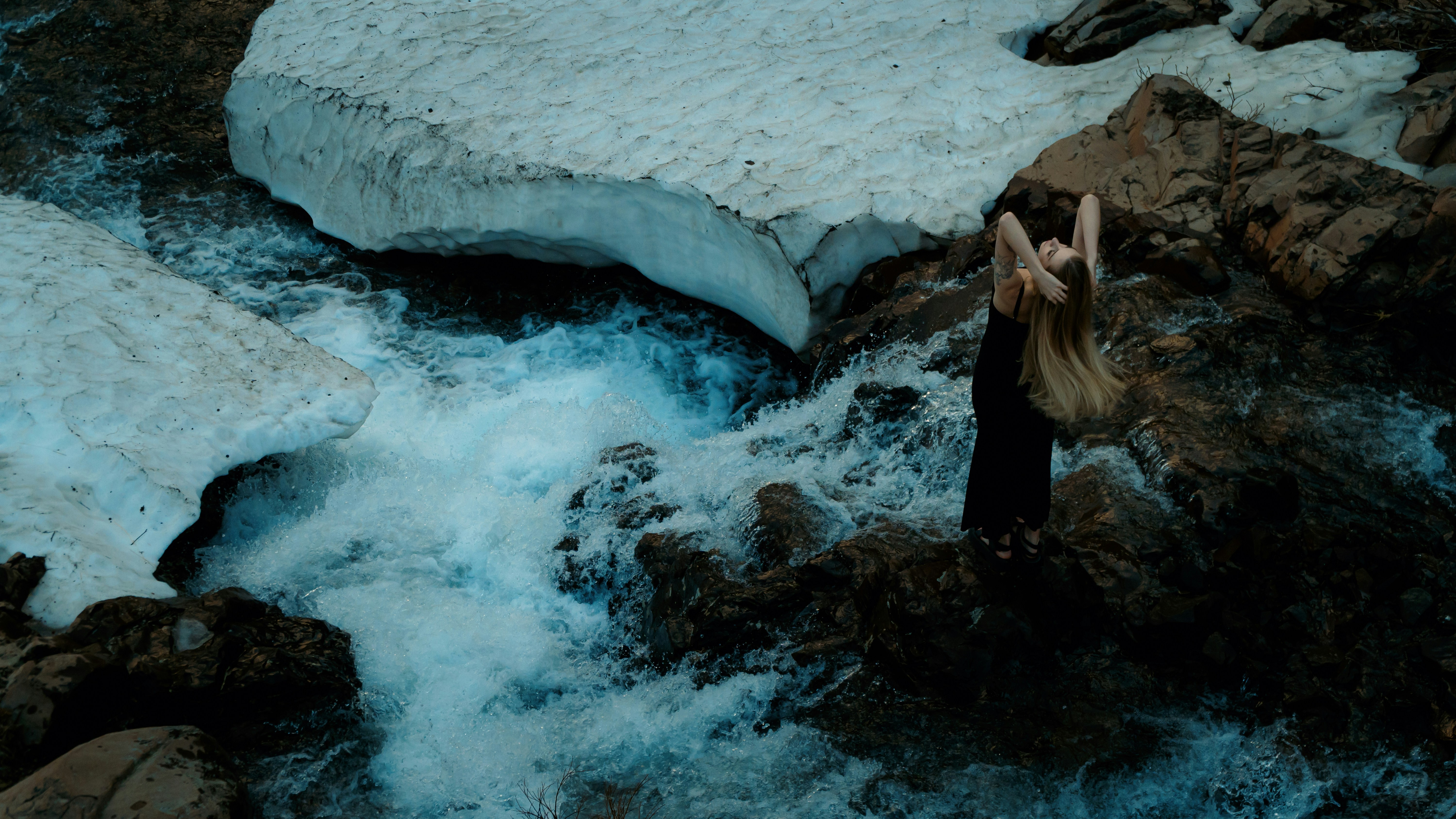 A woman standing on a rock next to a river